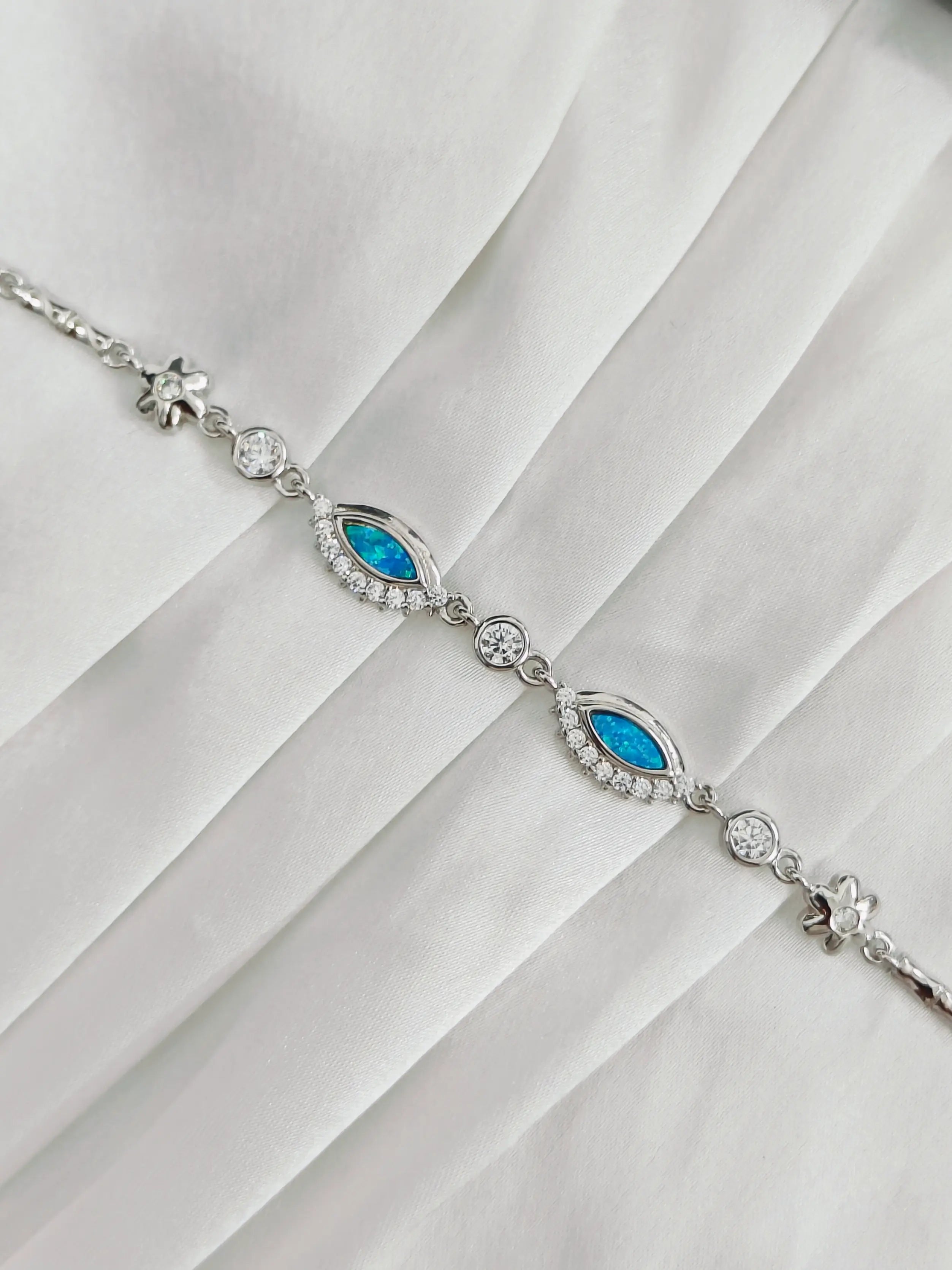 Silver bracelet with blue stones on a white fabric background