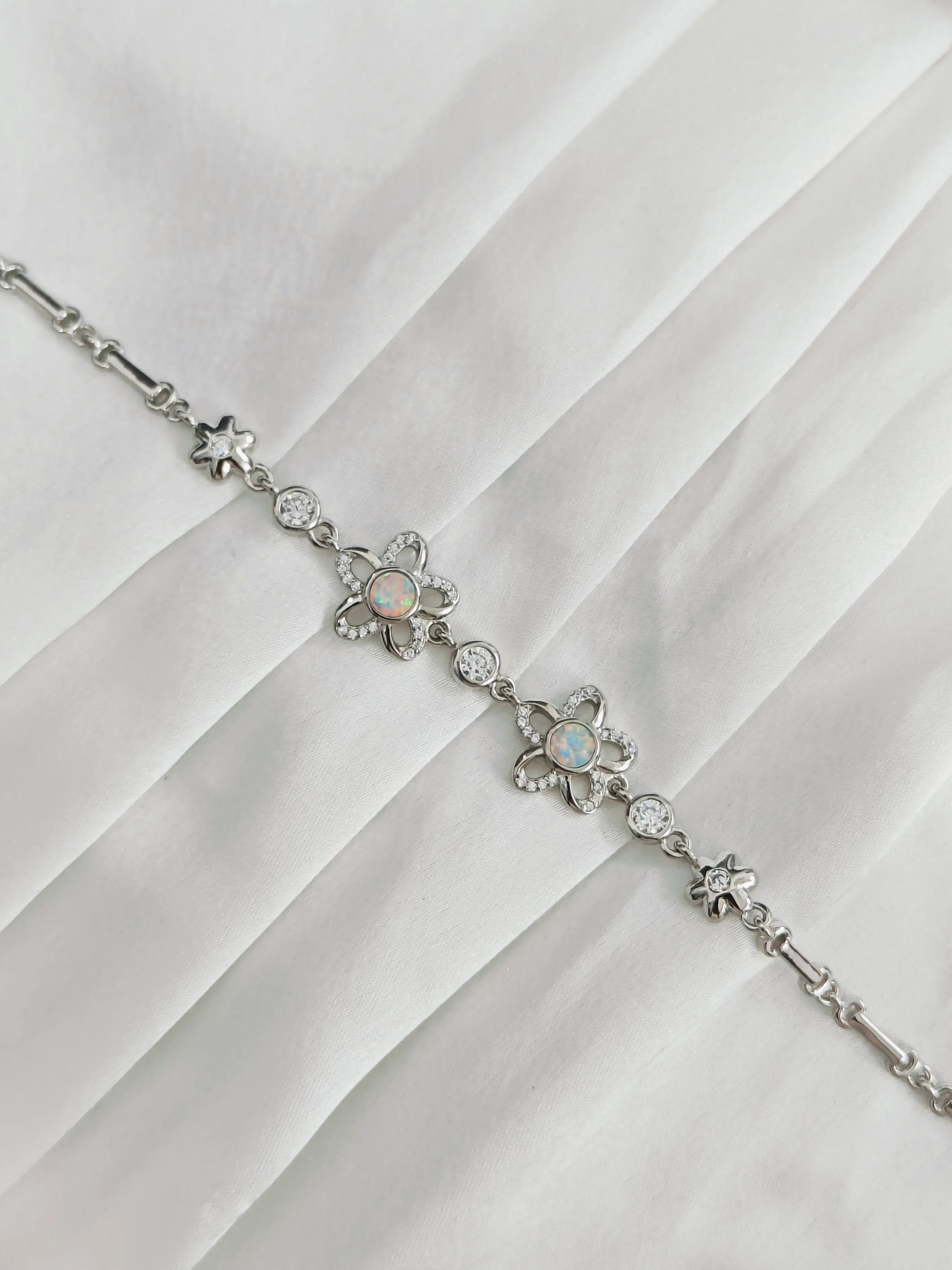 Silver bracelet with floral designs on a white fabric background