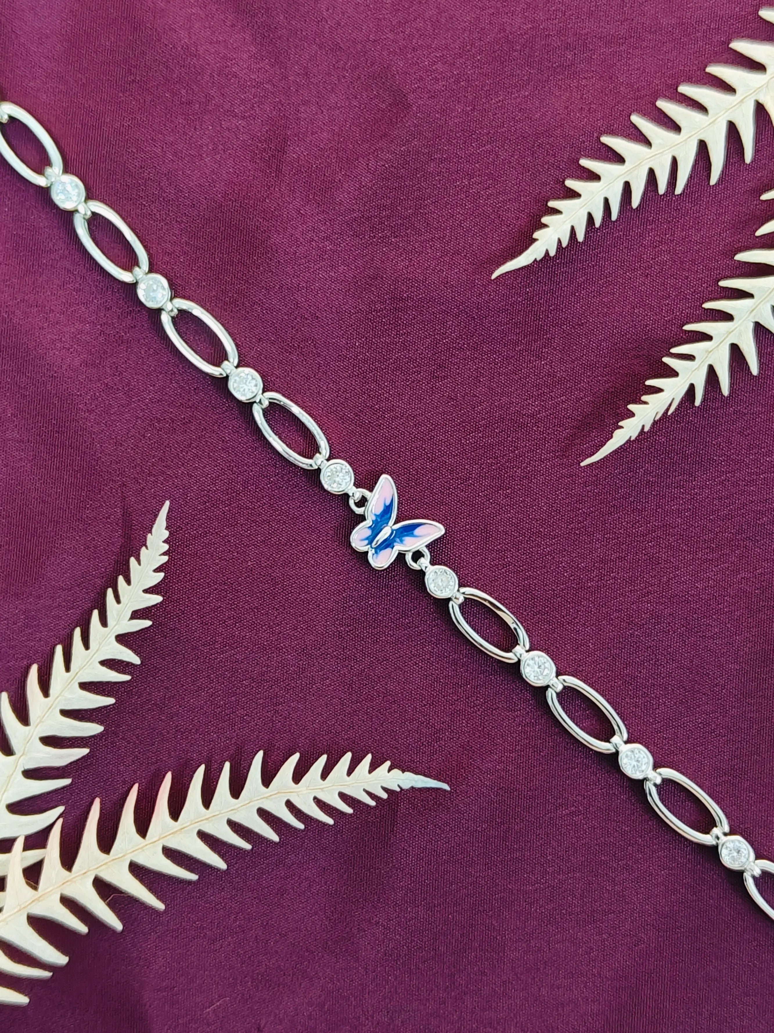 Silver bracelet with a butterfly charm on a purple fabric background