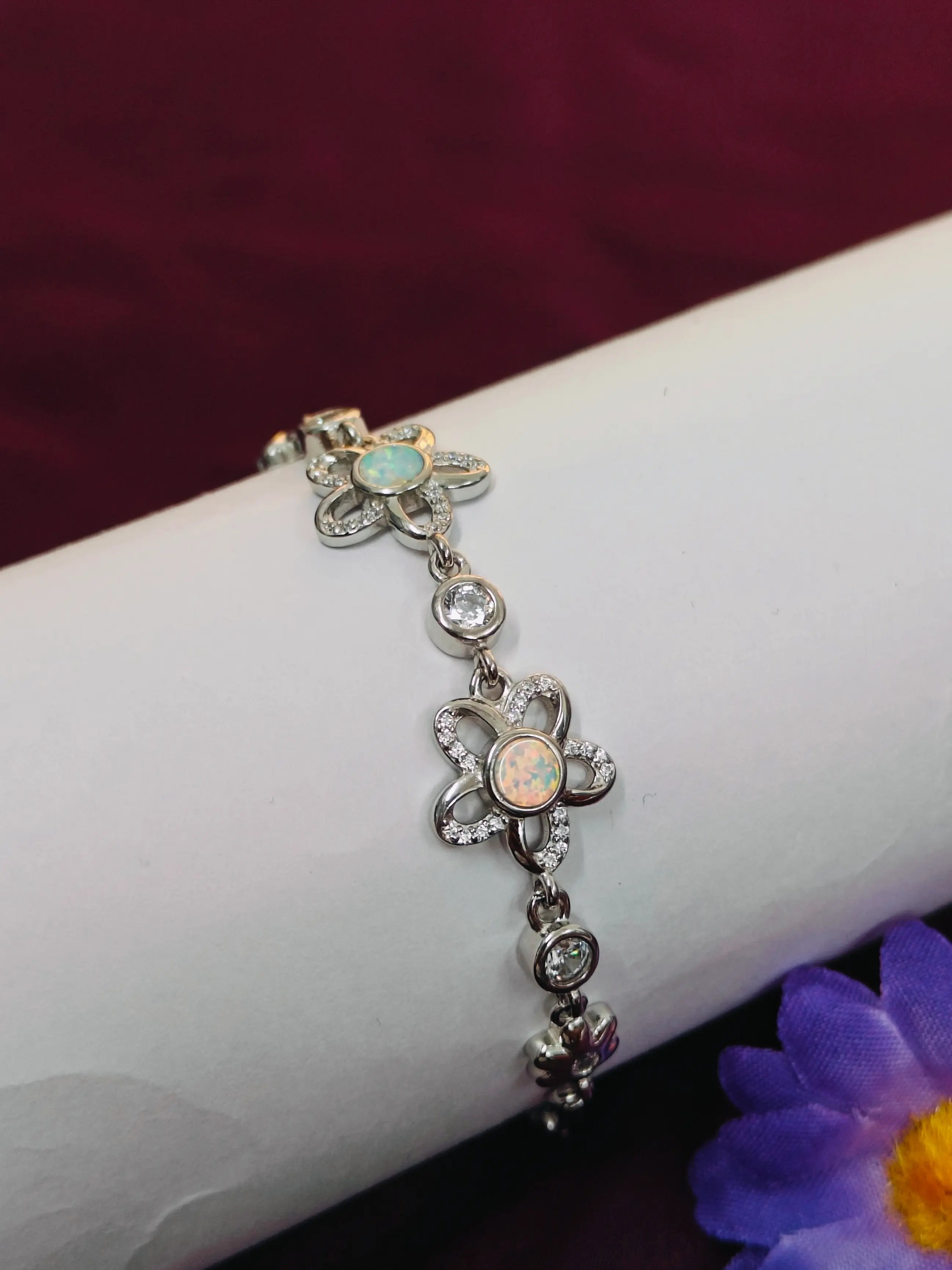Silver bracelet with floral charms on a wrist against a dark background