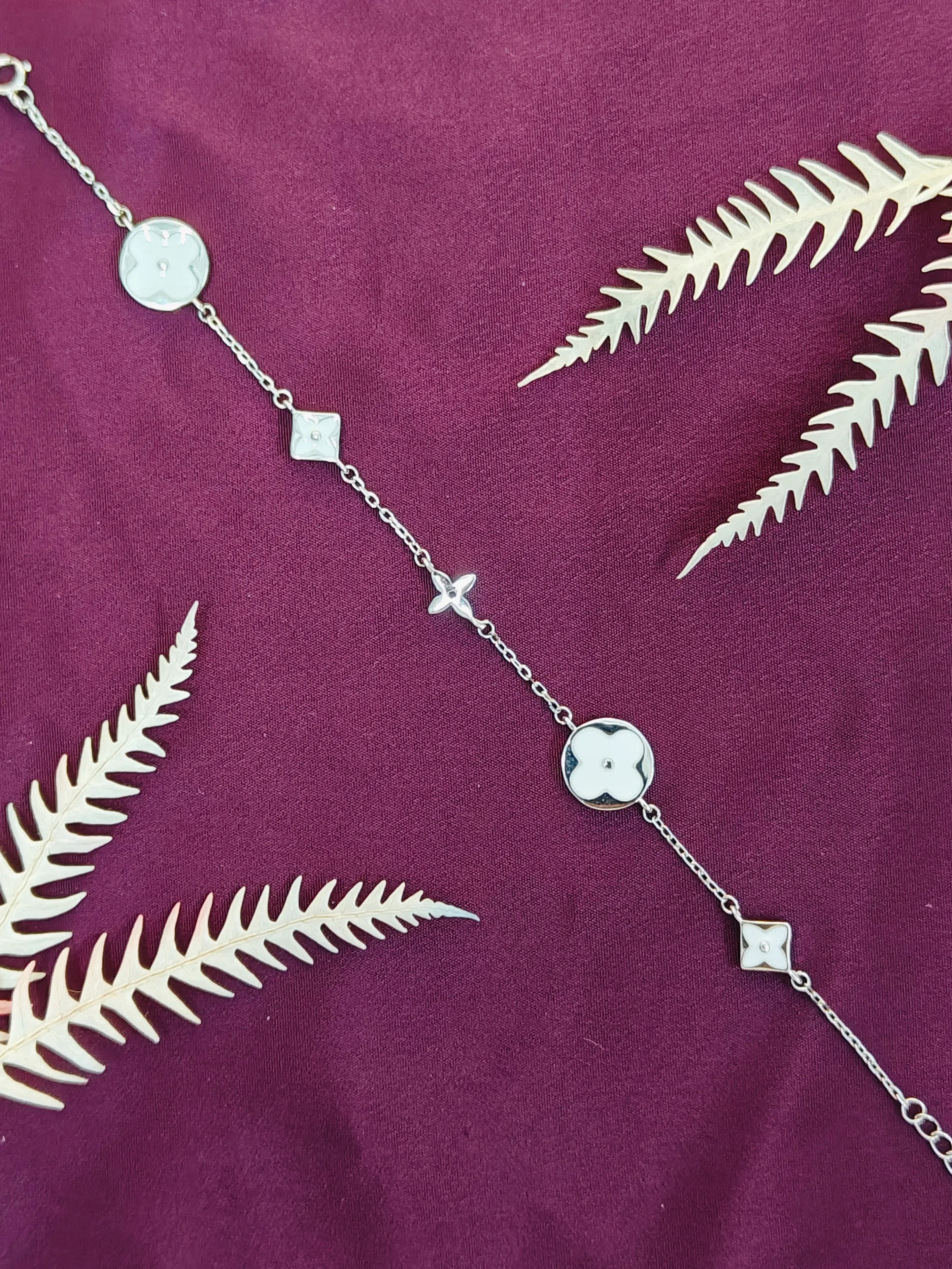 Silver chain necklace with leaf pendants on a purple fabric background
