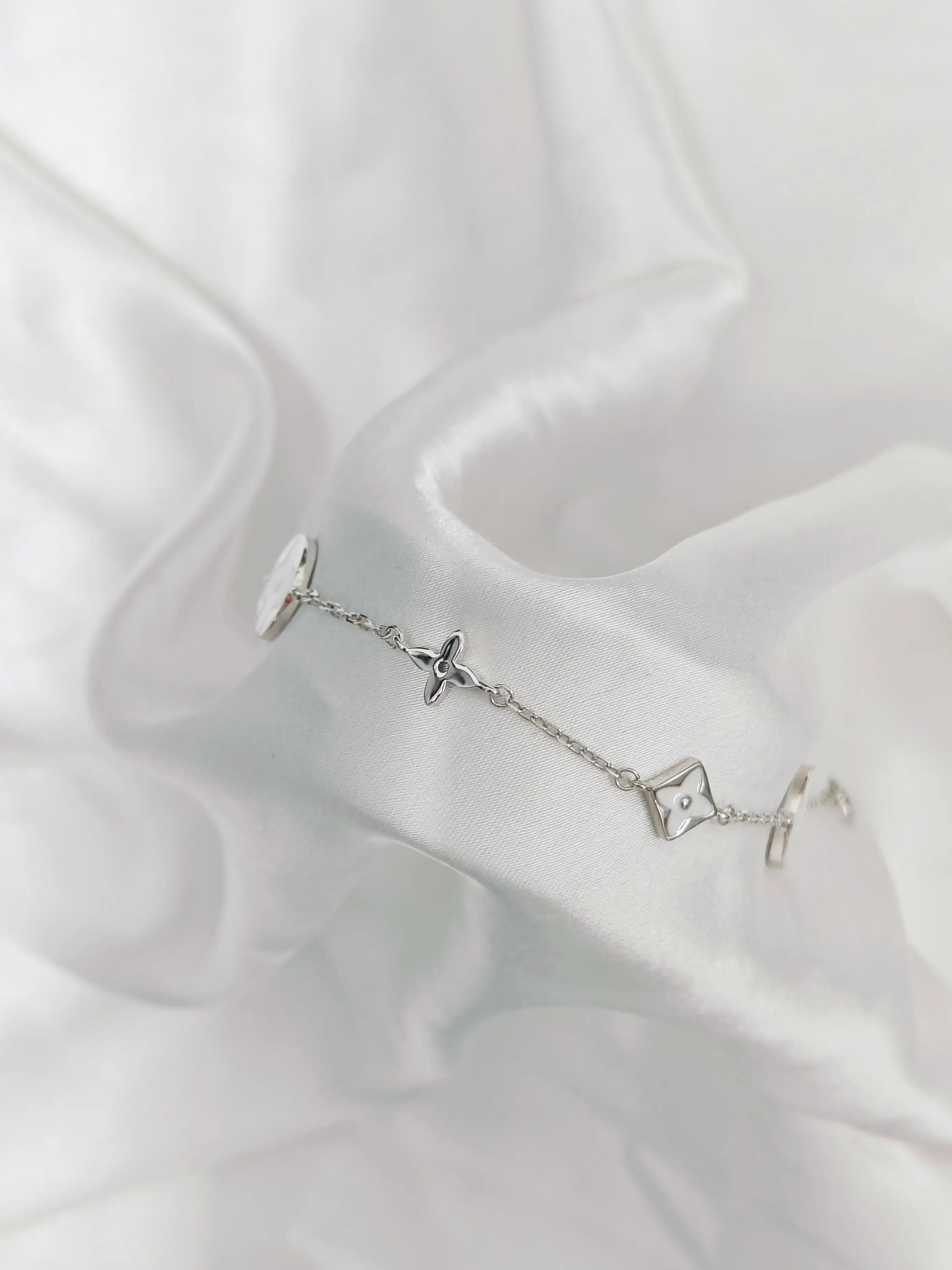 Silver bracelet with star-shaped charms on a white fabric background