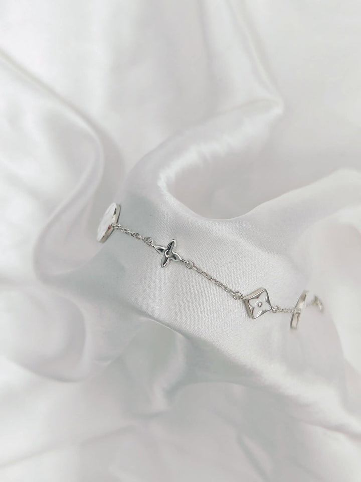 Silver bracelet with star-shaped charms on a white fabric background
