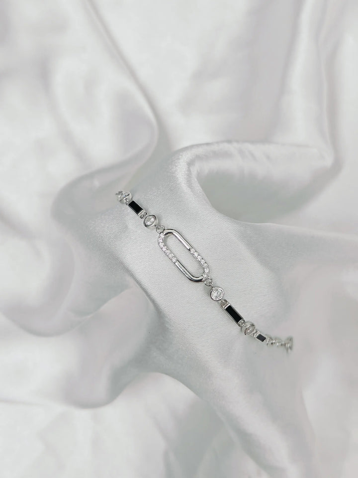Silver bracelet with black accents on a white fabric background