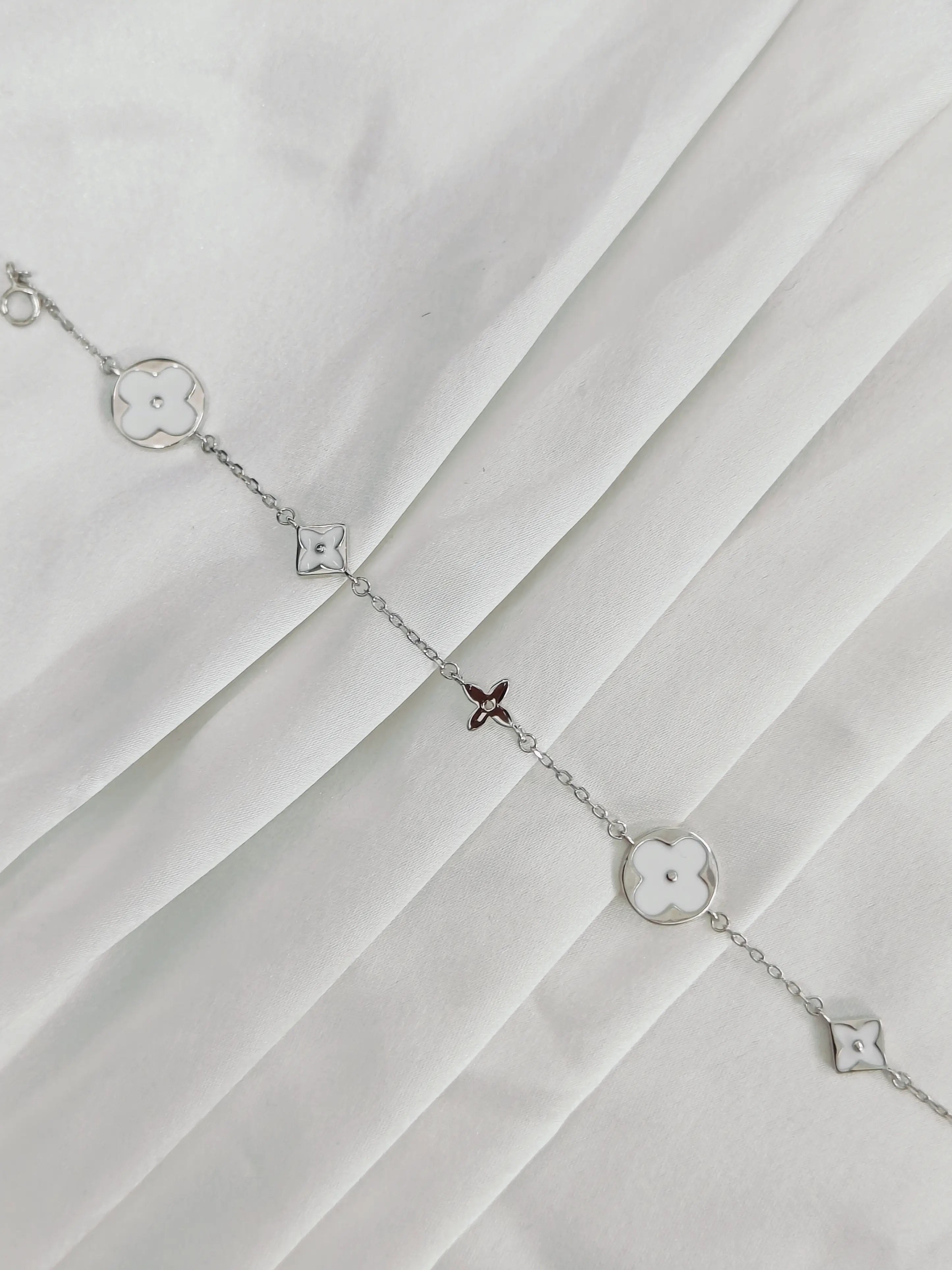 Silver bracelet with star-shaped charms on a white fabric background