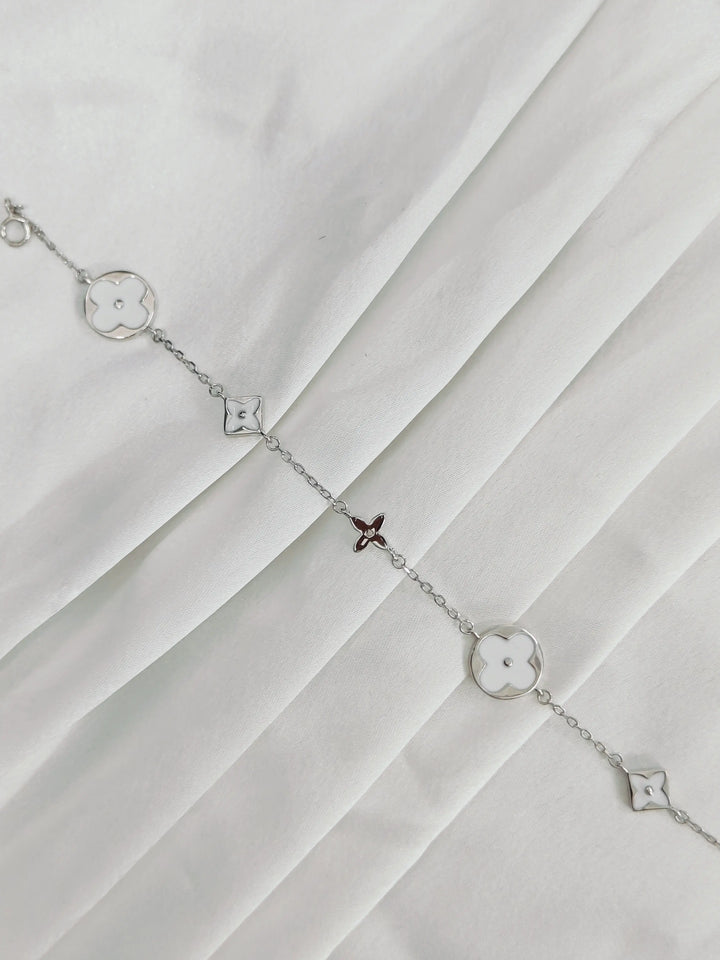 Silver bracelet with star-shaped charms on a white fabric background