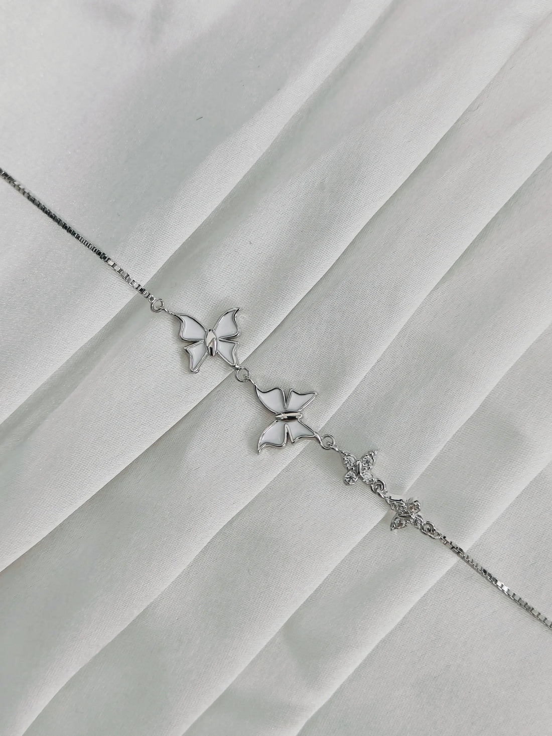 Silver butterfly bracelet on a textured white surface