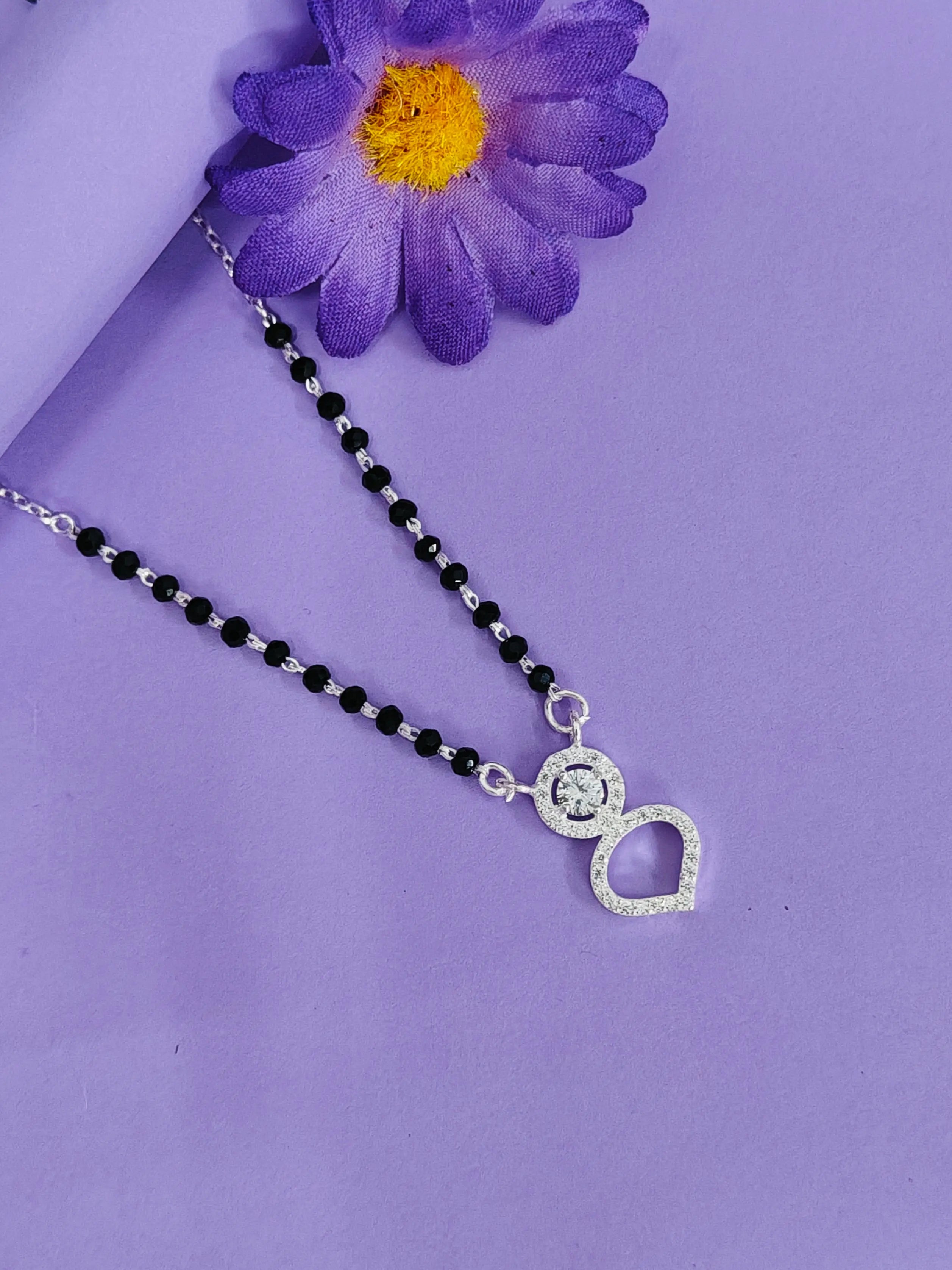 Necklace with a heart and circle pendant on a purple background with a purple flower.