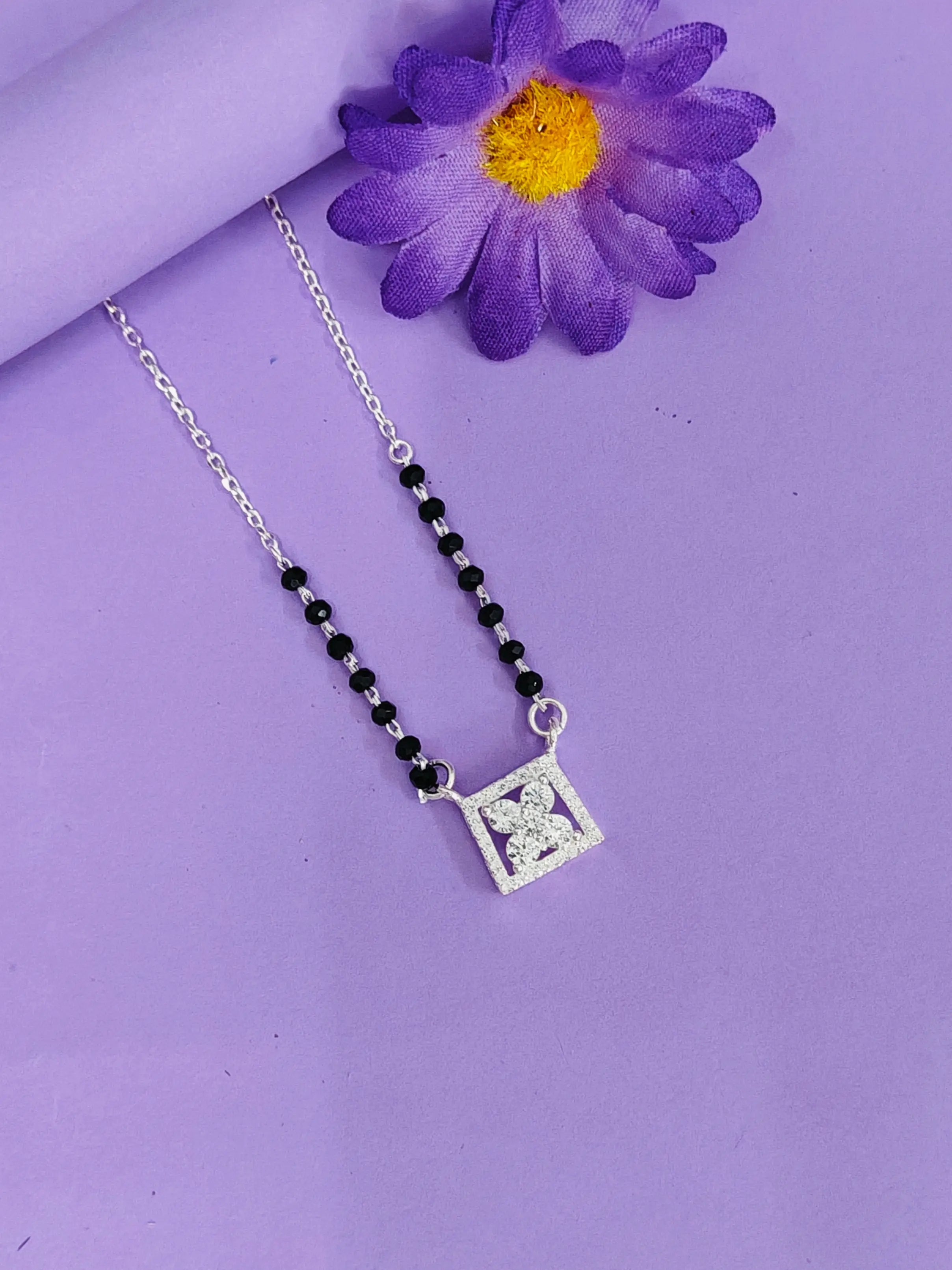 Necklace with a square pendant on a purple background with a purple flower.