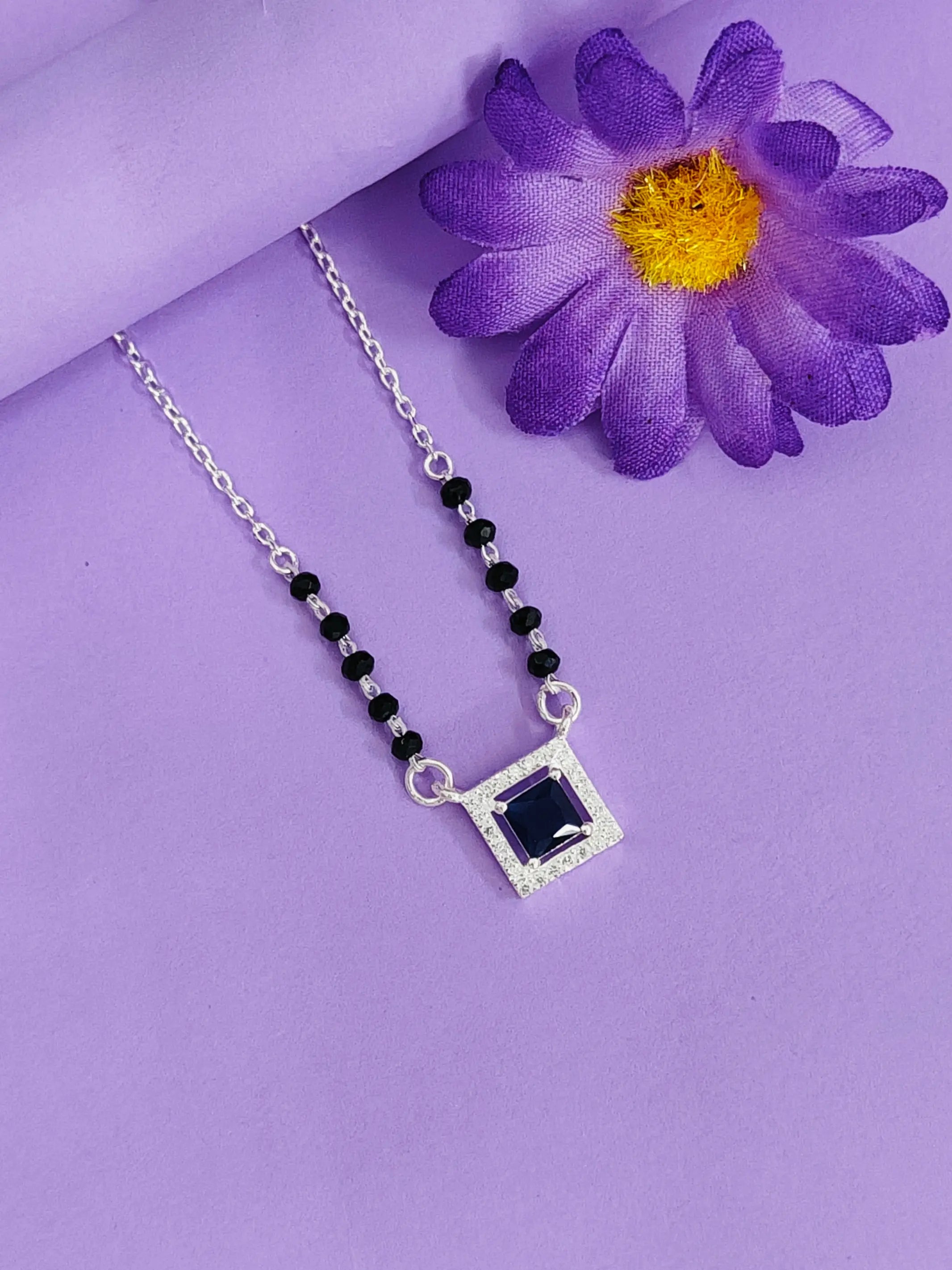 Necklace with a square pendant on a purple background with a purple flower