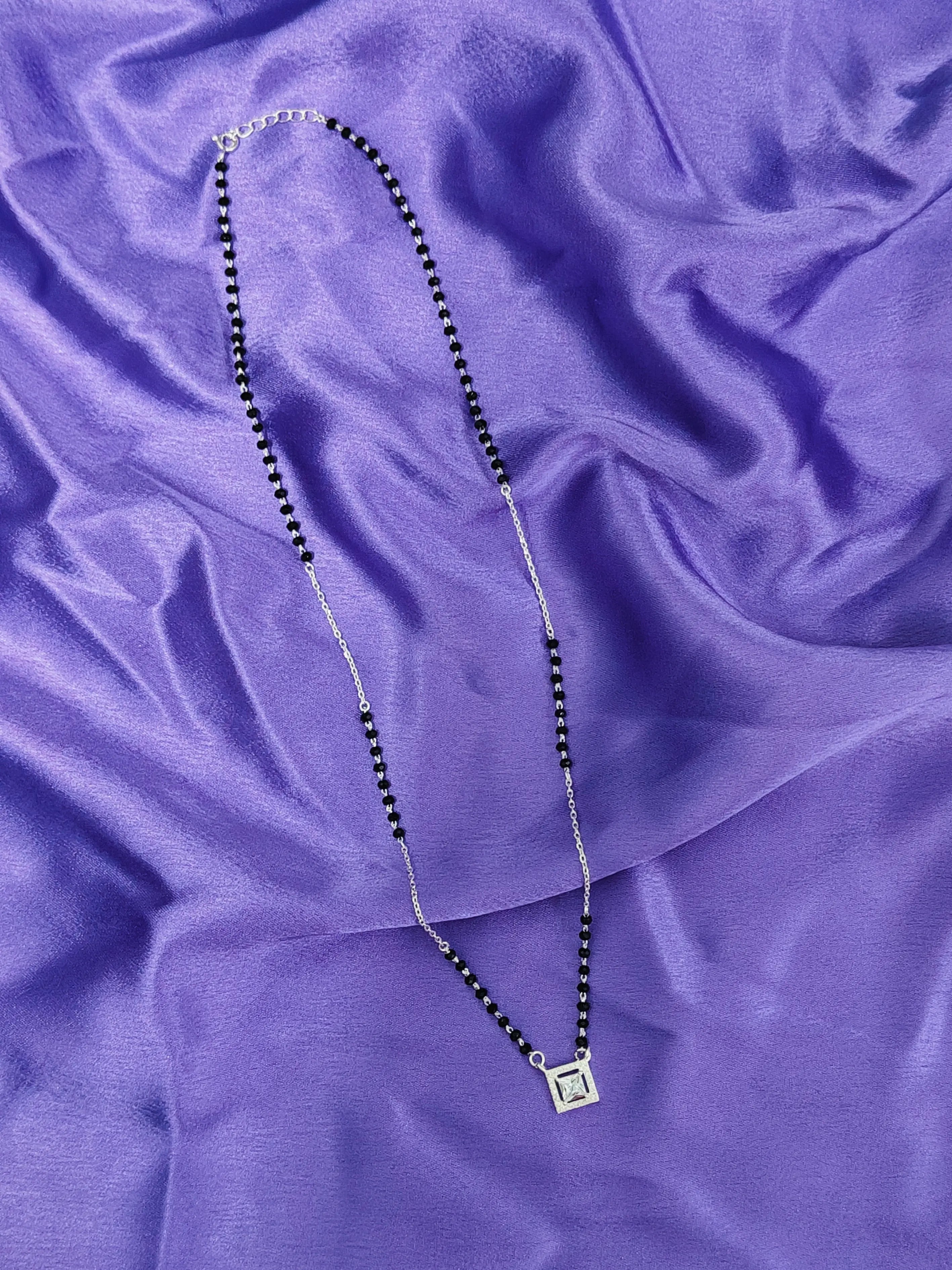 Necklace with a square pendant on a purple fabric background