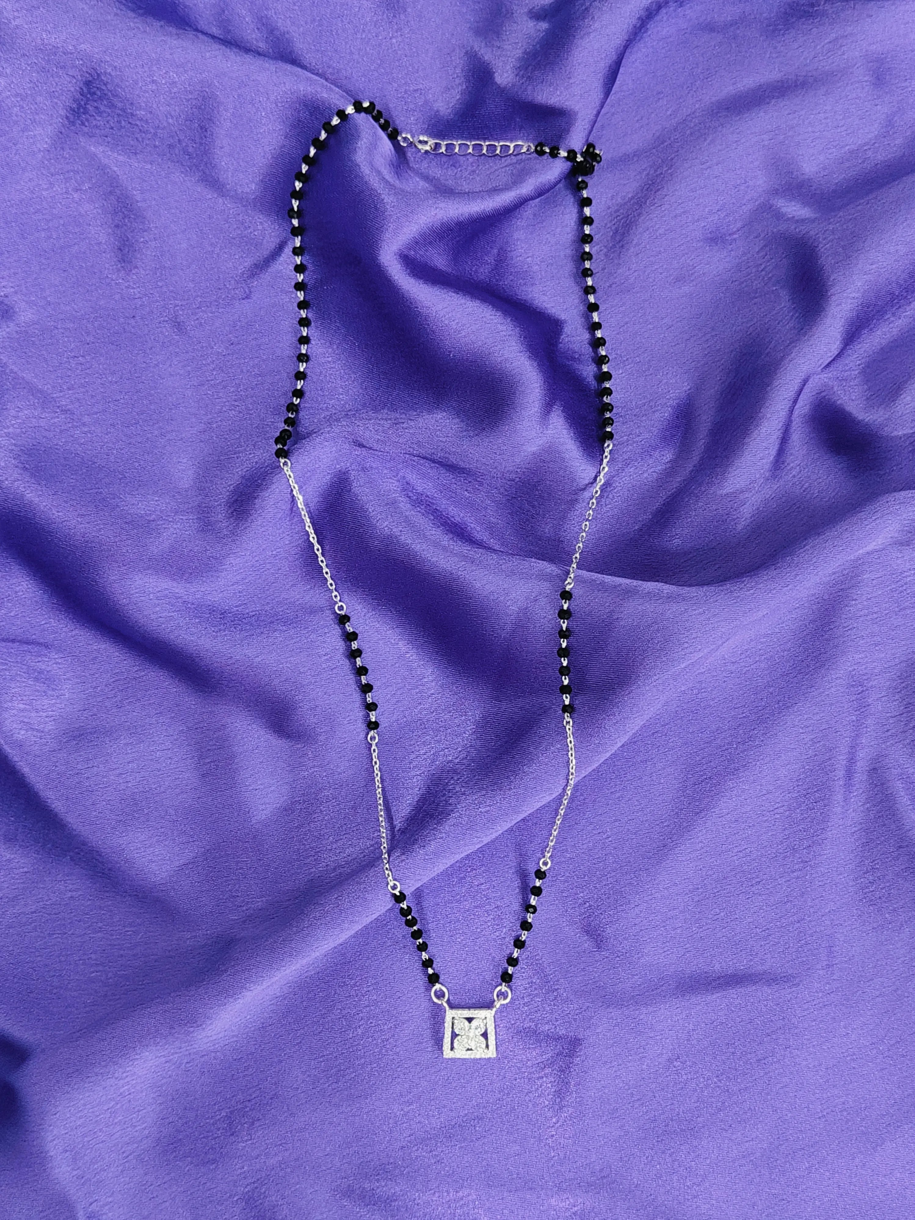 Necklace with a square pendant on a purple fabric background