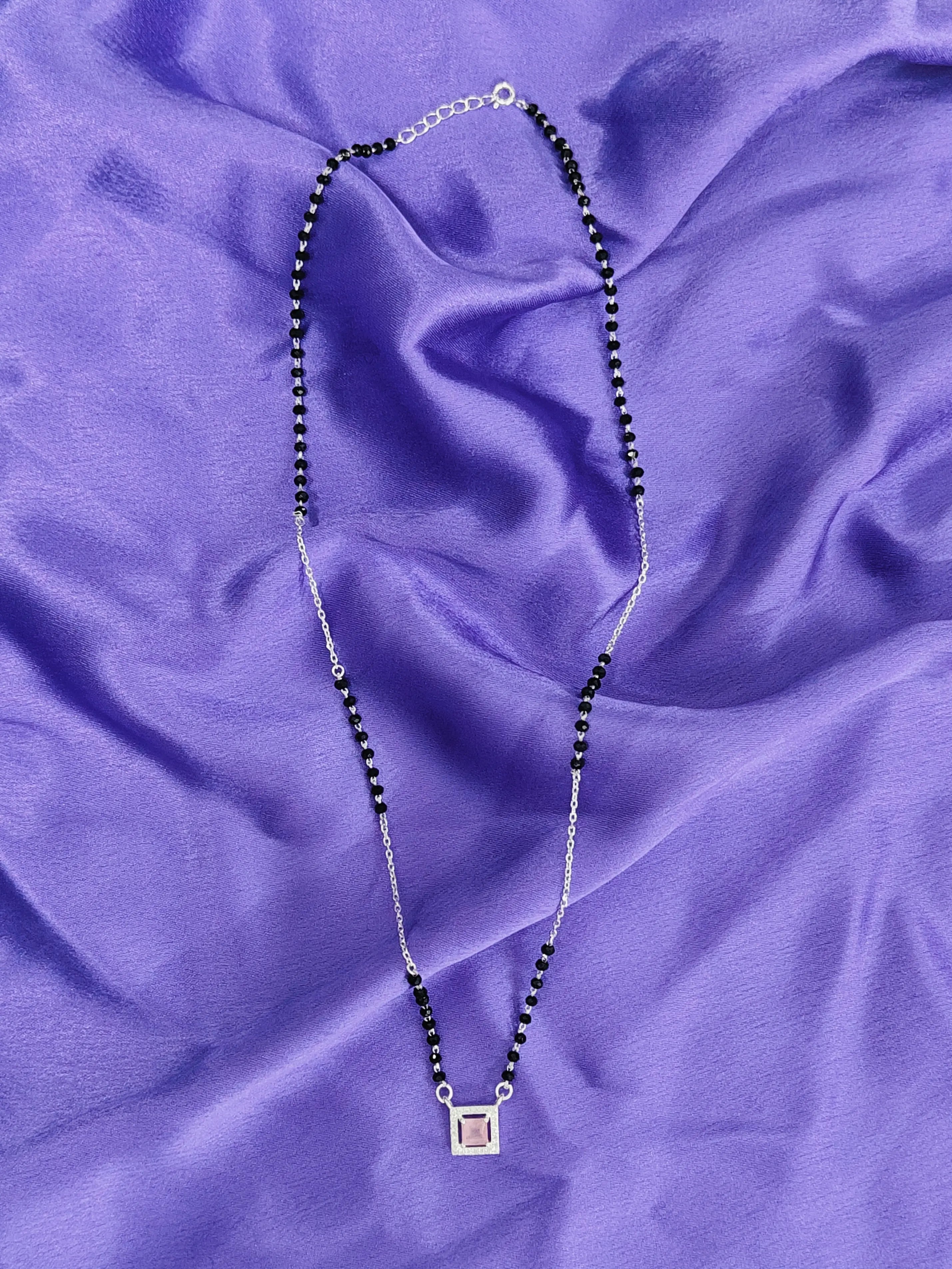 Necklace with a square pendant on a purple fabric background