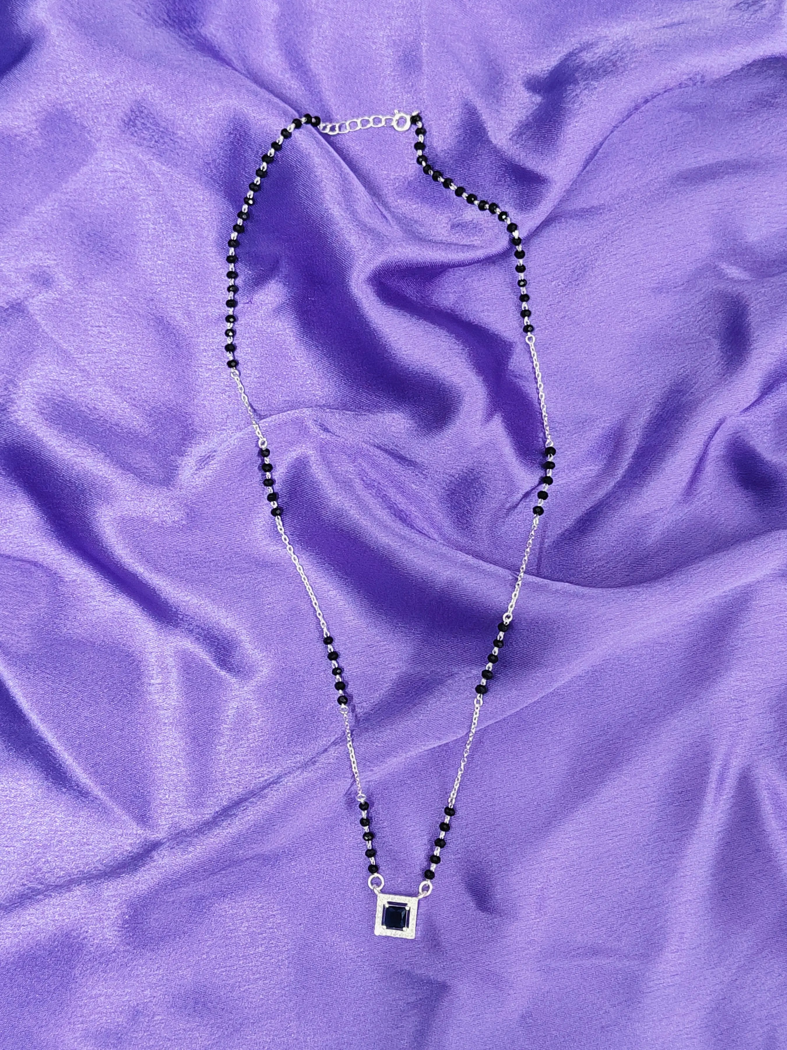 Necklace with a square pendant on a purple fabric background