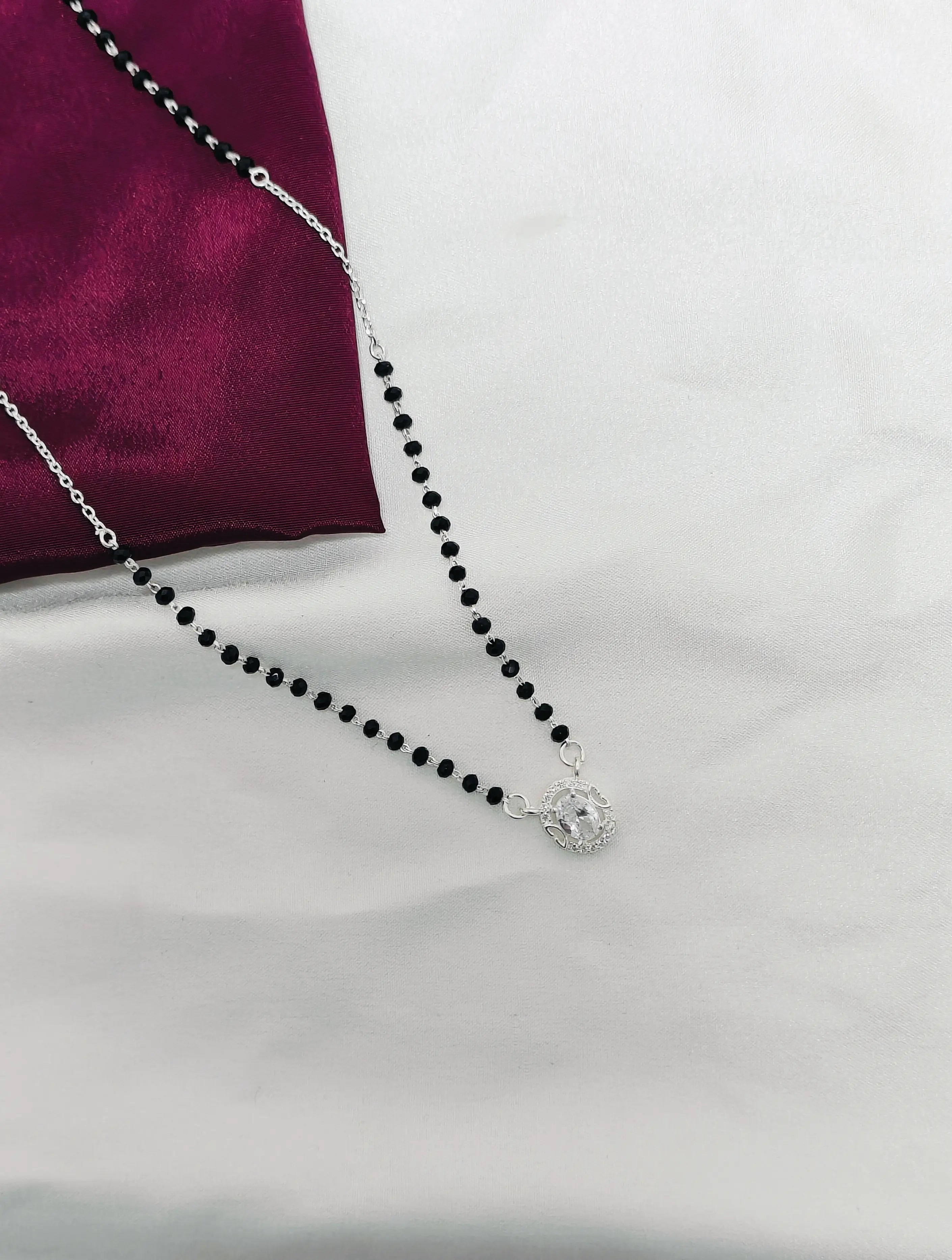 Black beaded necklace with a silver clasp on a white background