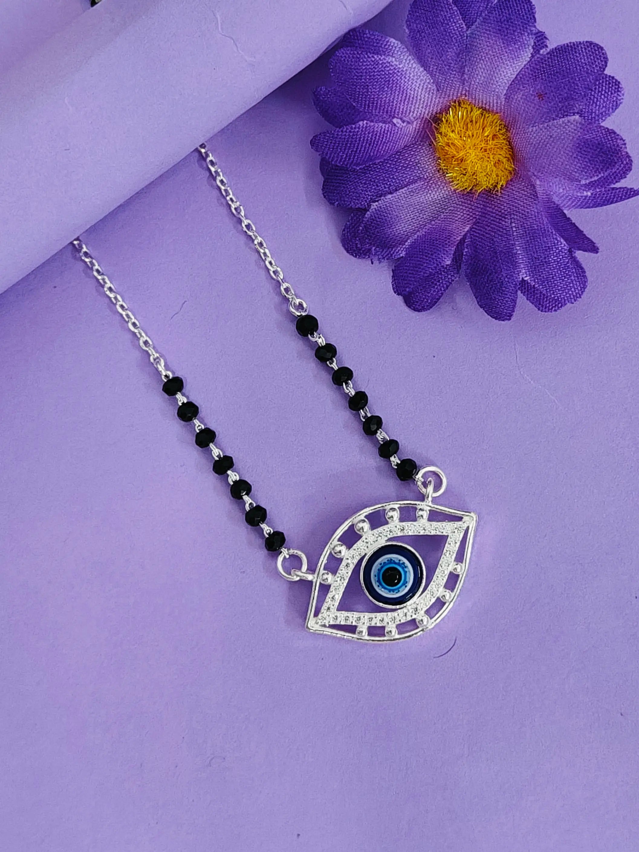 Necklace with eye pendant on a purple background with a purple flower