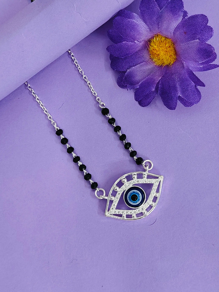 Necklace with eye pendant on a purple background with a purple flower