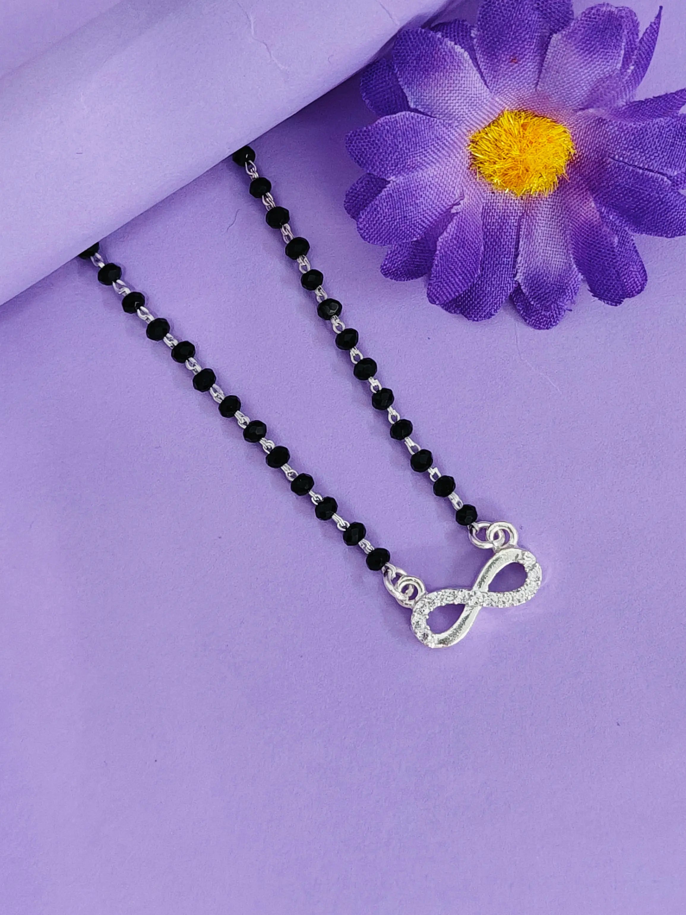 Necklace with an infinity symbol pendant on a purple background with a purple flower.
