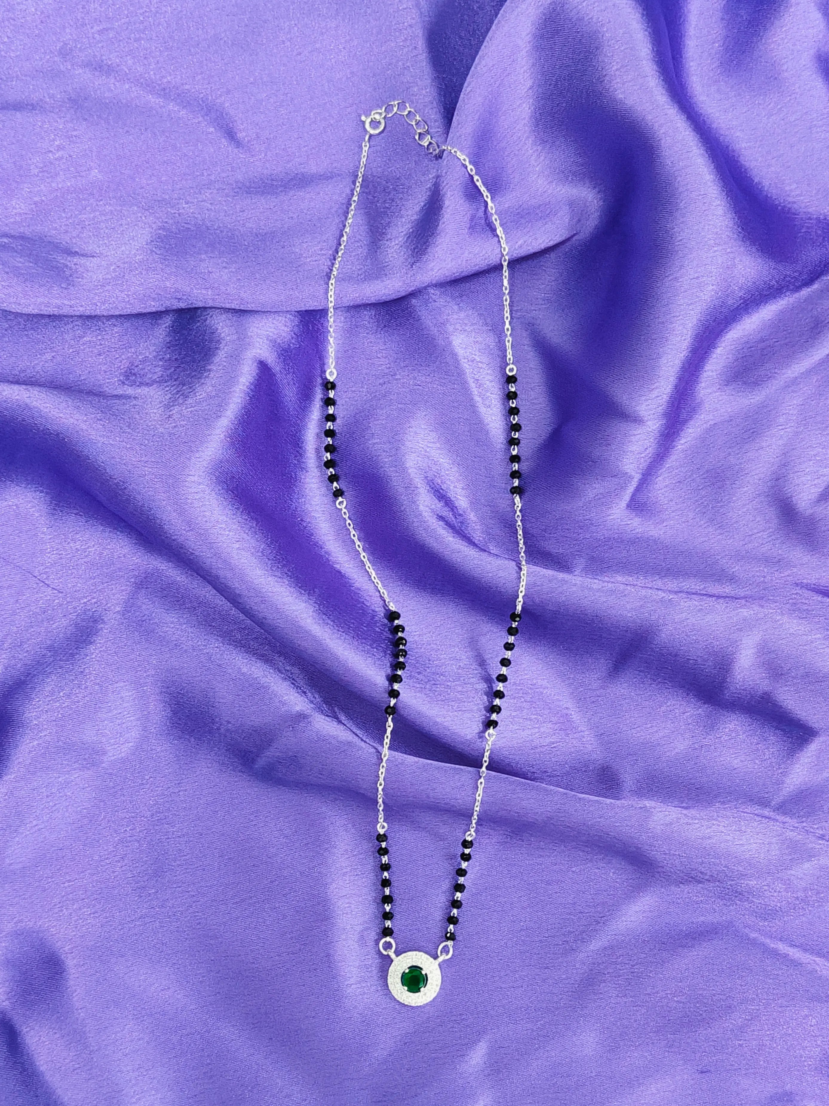 Necklace with a green pendant on a purple fabric background