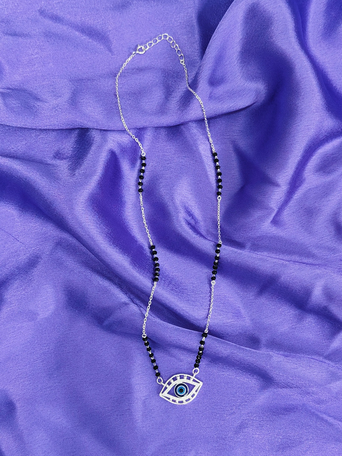 Necklace with an eye pendant on a purple fabric background