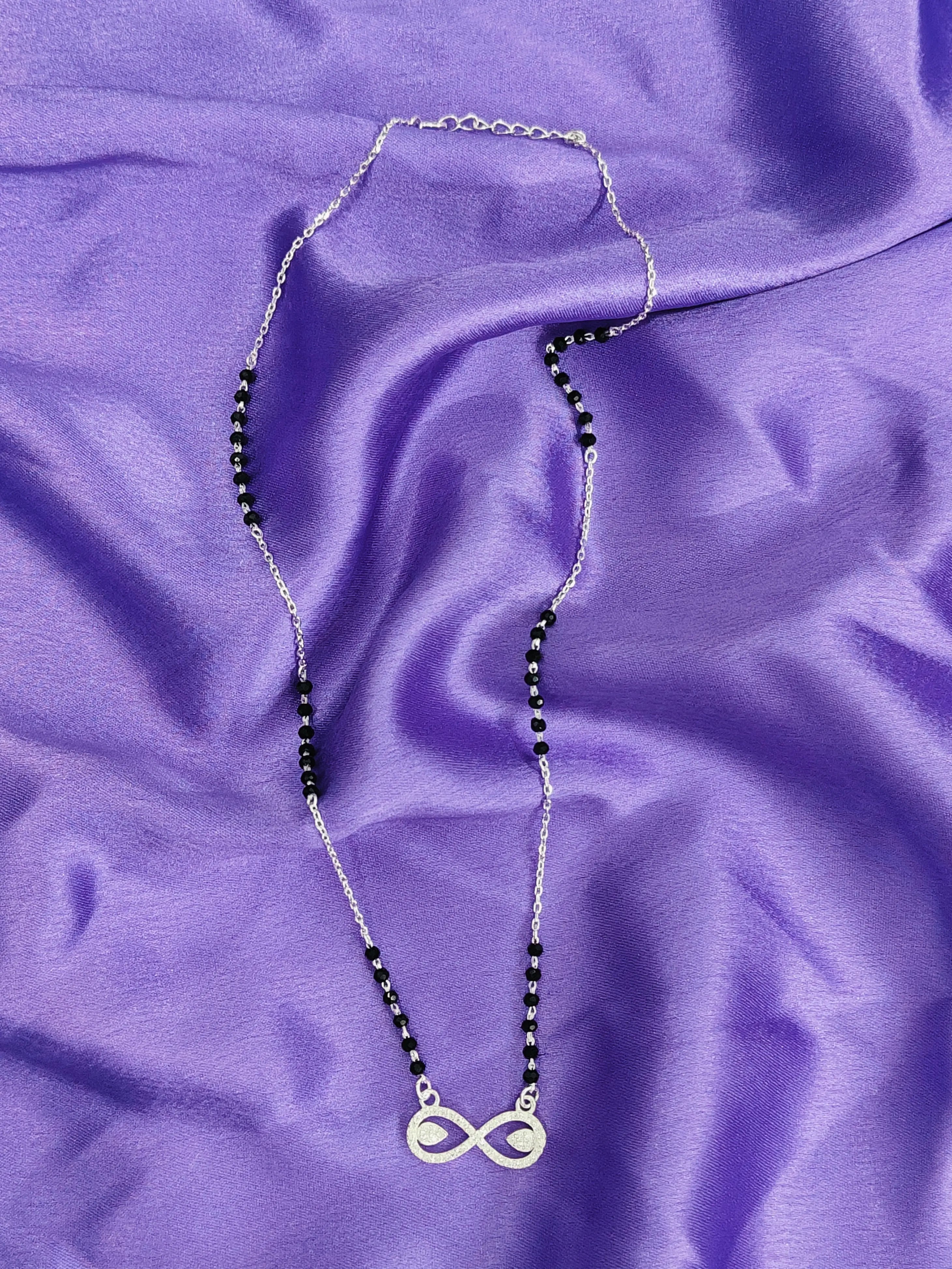 Necklace with an infinity symbol pendant on a purple fabric background