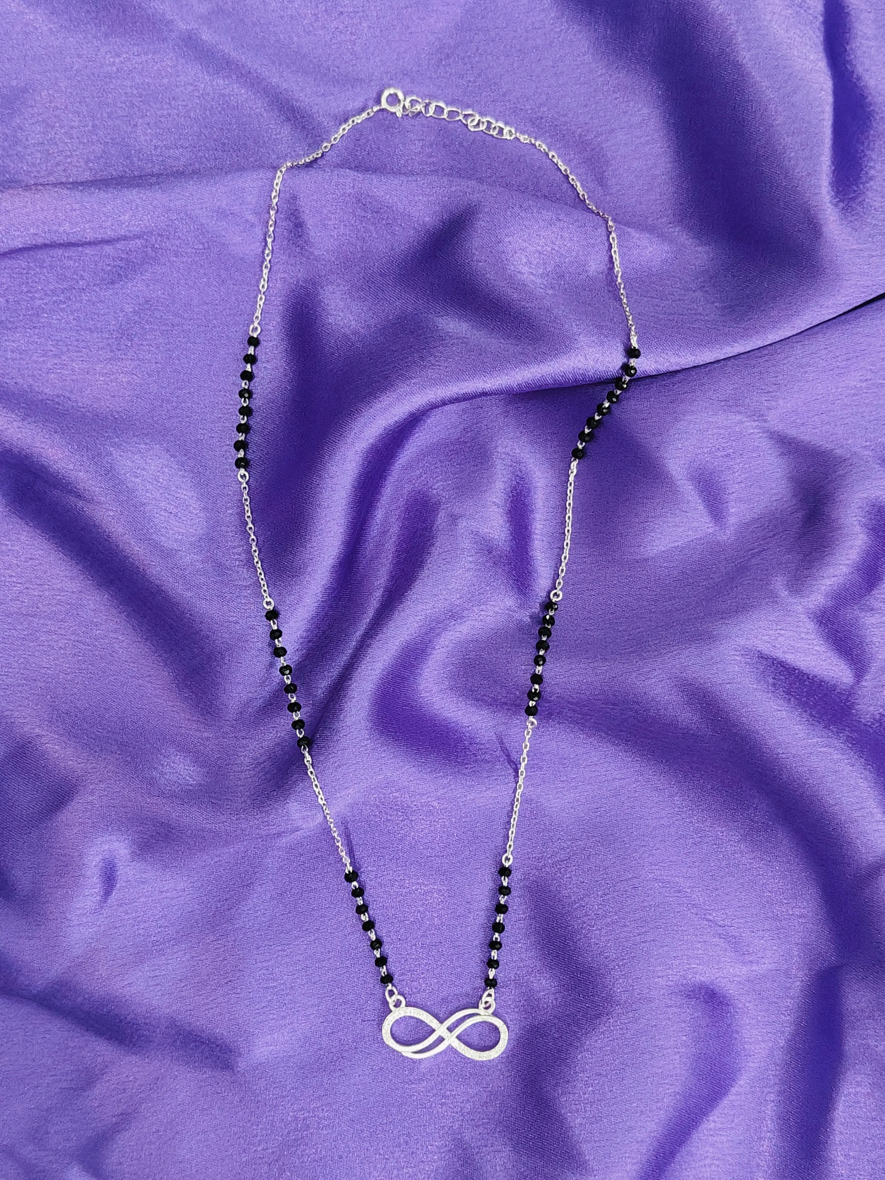 Necklace with an infinity symbol pendant on a purple fabric background