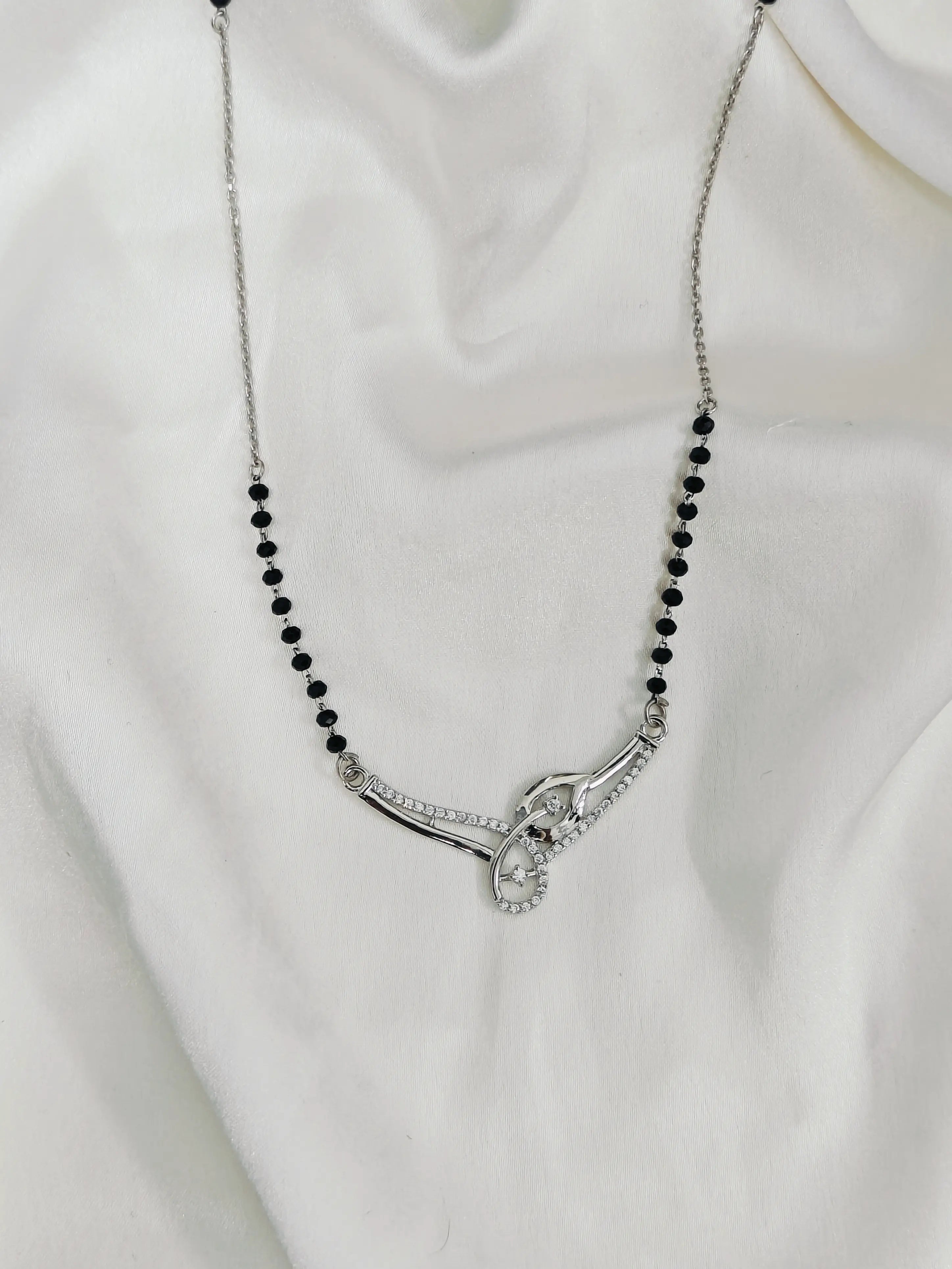 Necklace with black beads and silver clasp on a white fabric background