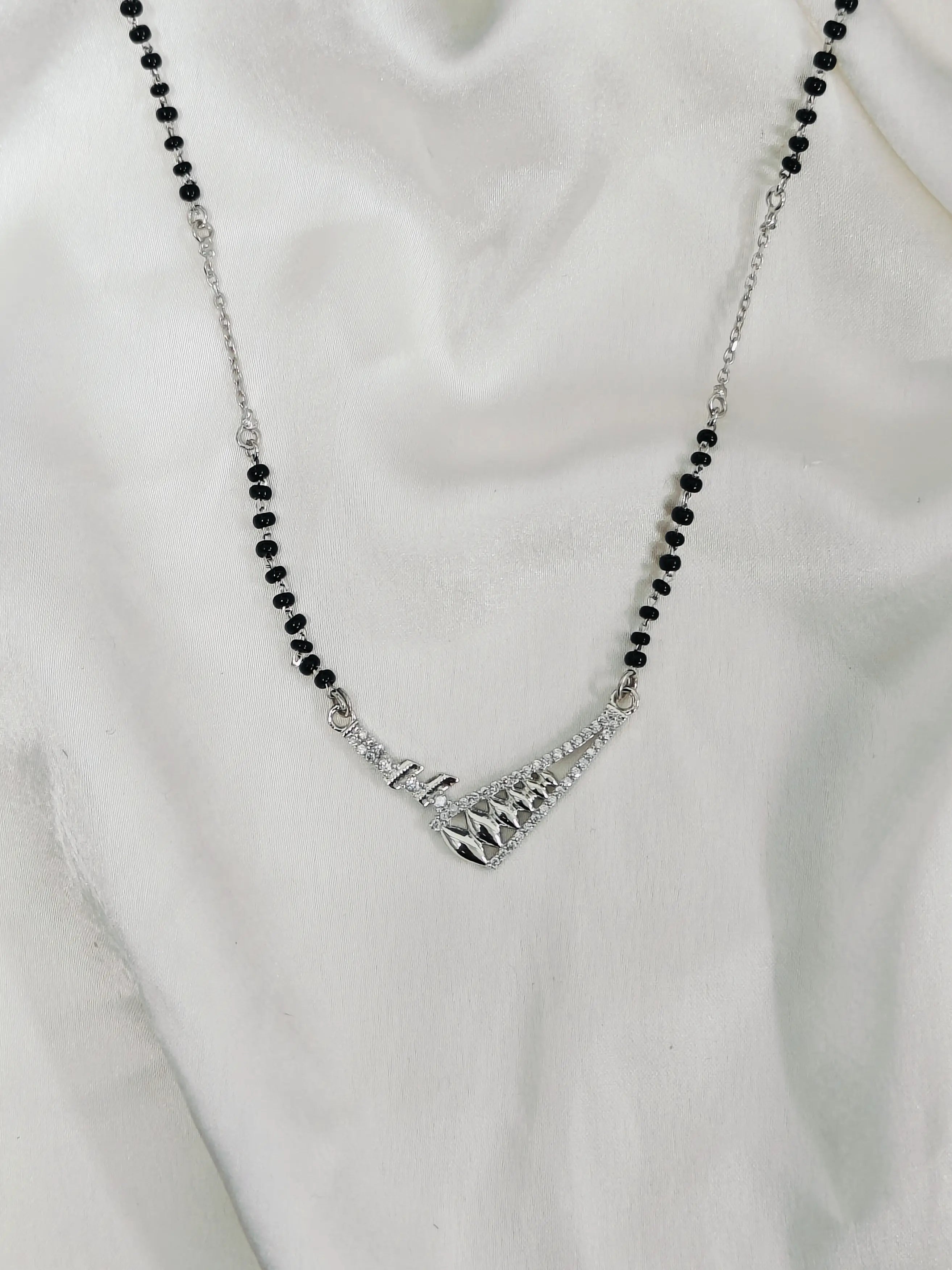 Necklace with black beads and silver clasp on a white fabric background