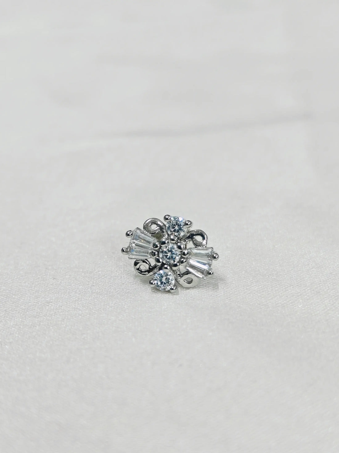 Silver earring with clear gemstones on a light gray background