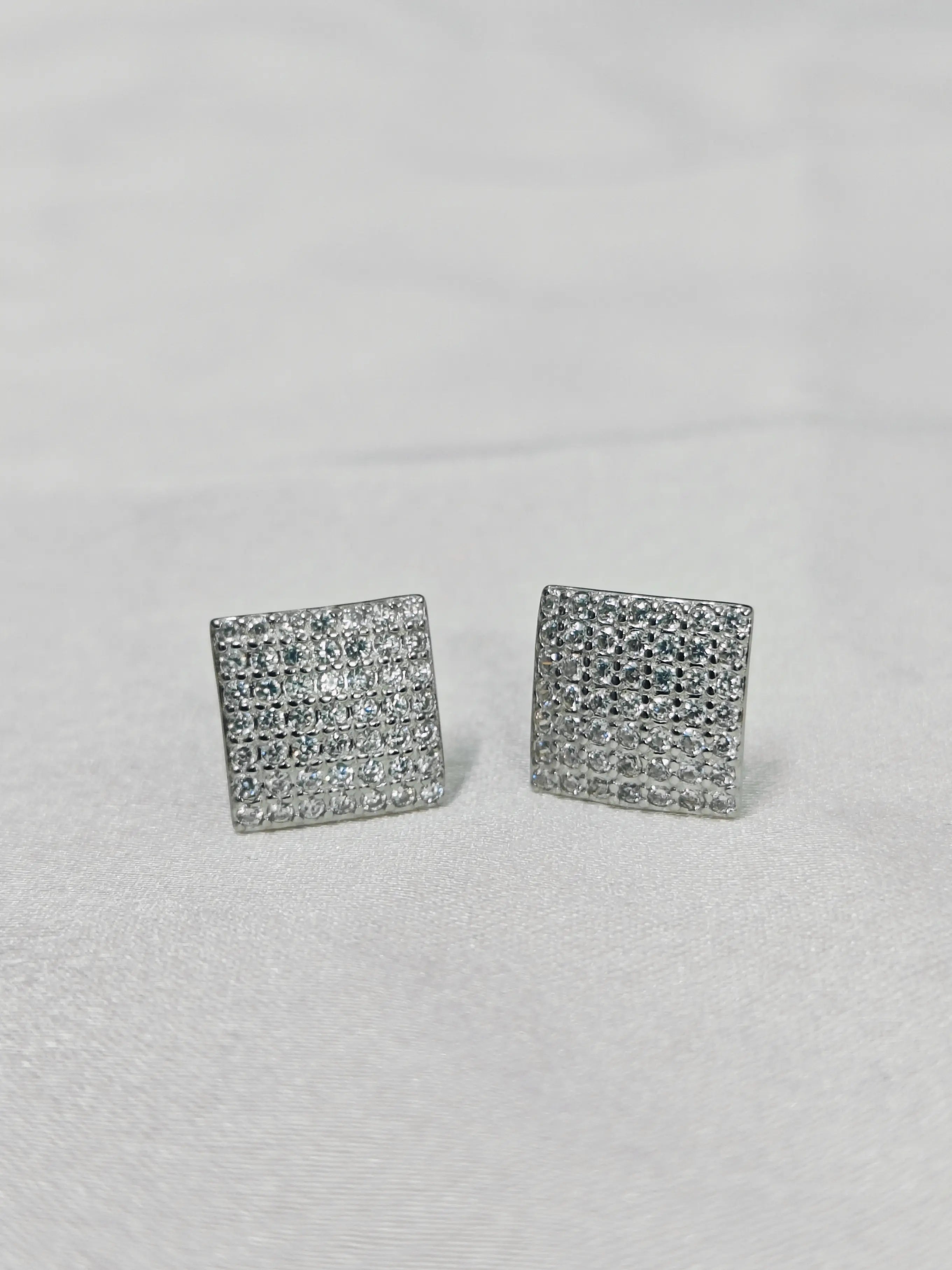 Pair of square-shaped silver earrings on a light gray background