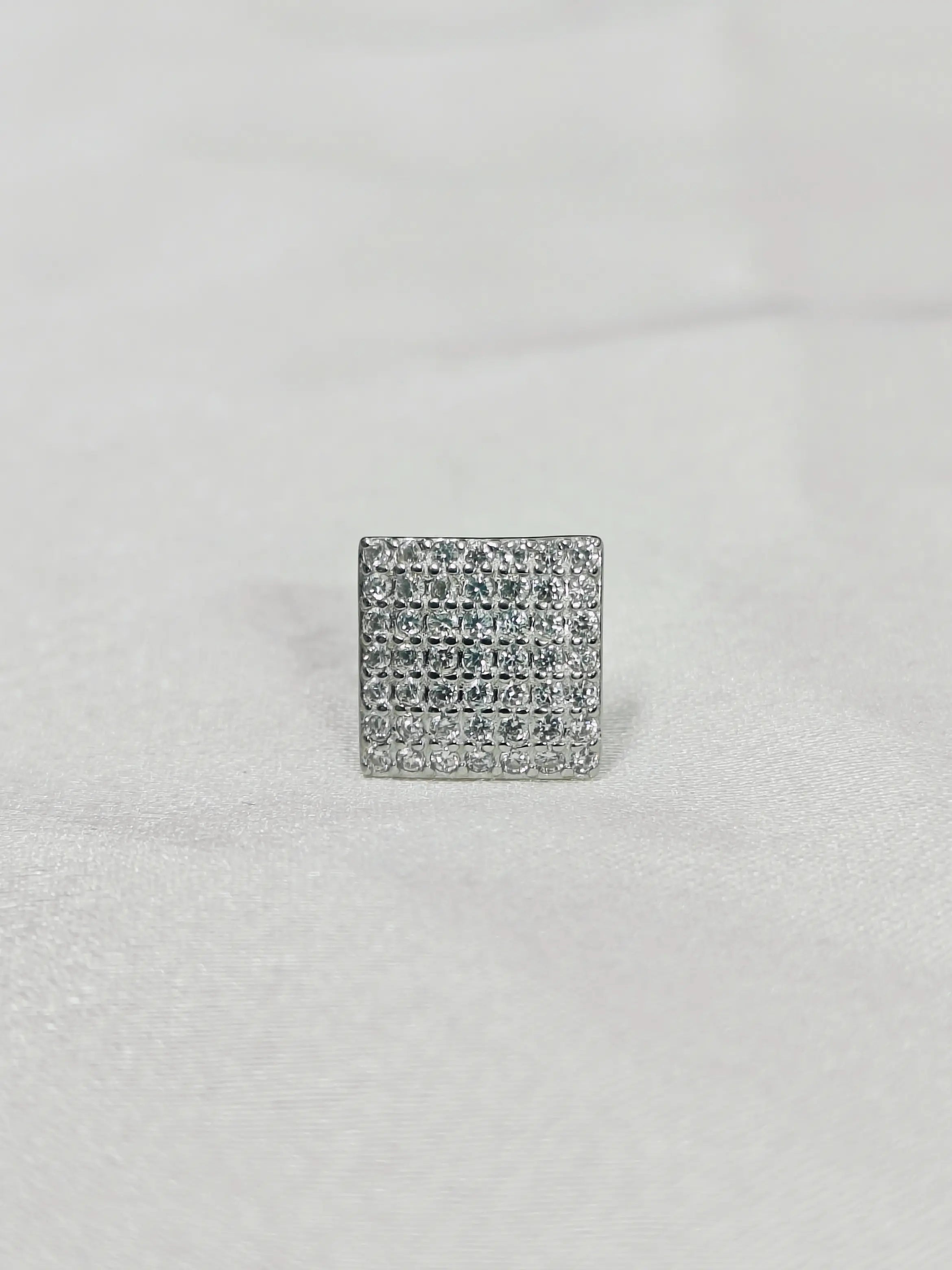 Silver square-shaped earring with clear stones on a light gray background