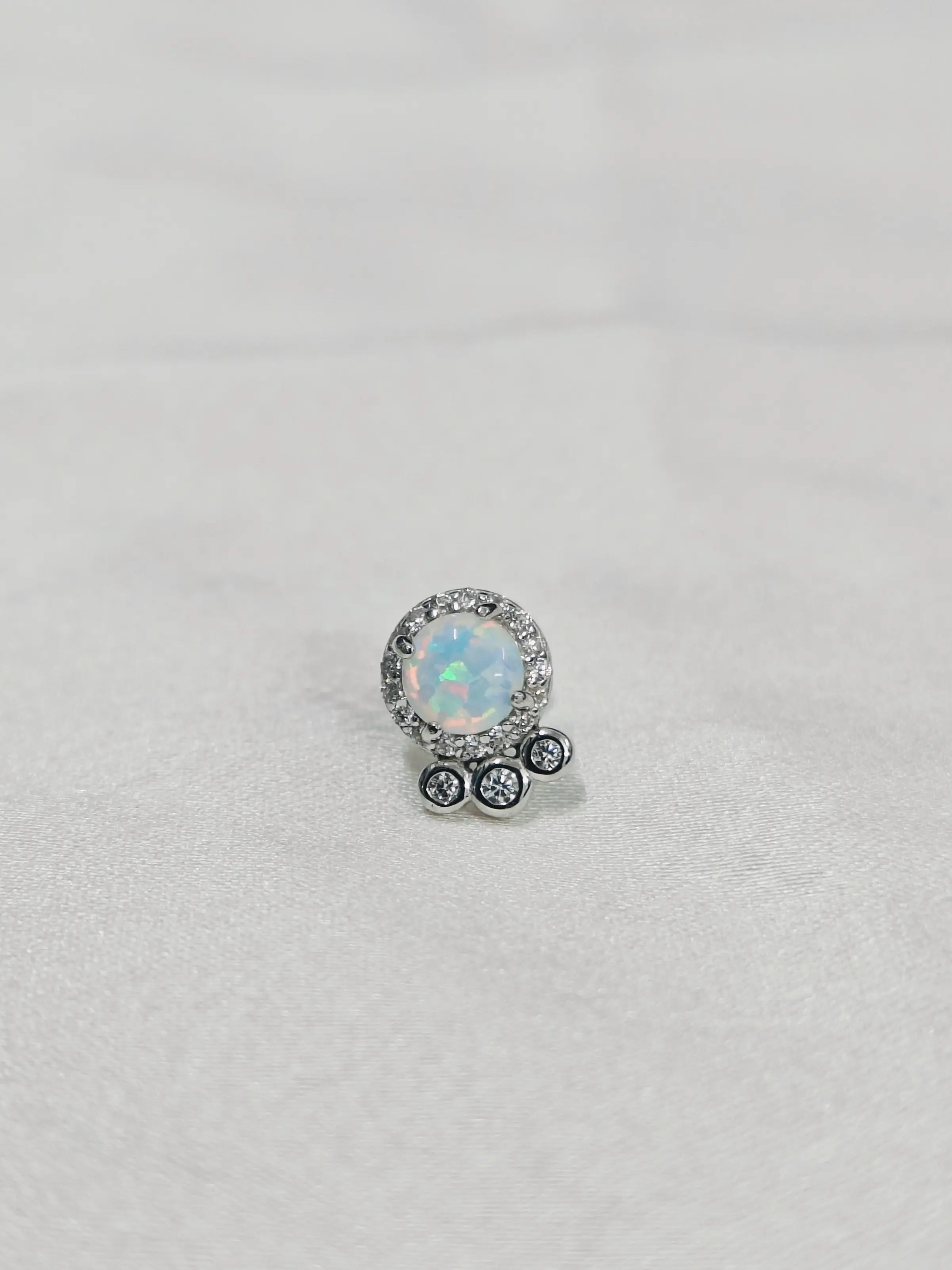 Silver earring with a central gemstone on a light gray background