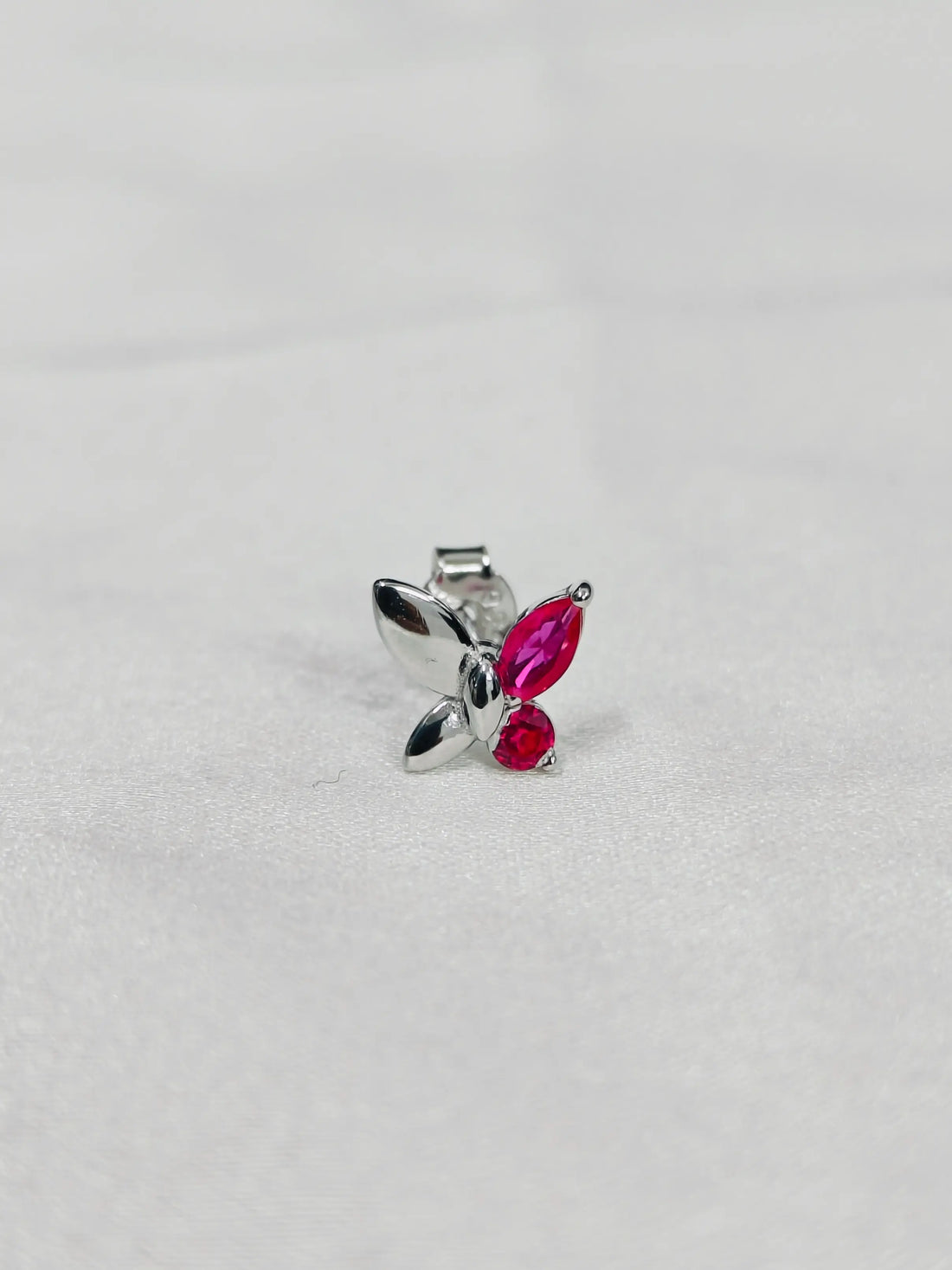 Silver butterfly pendant with red gemstones on a light gray background