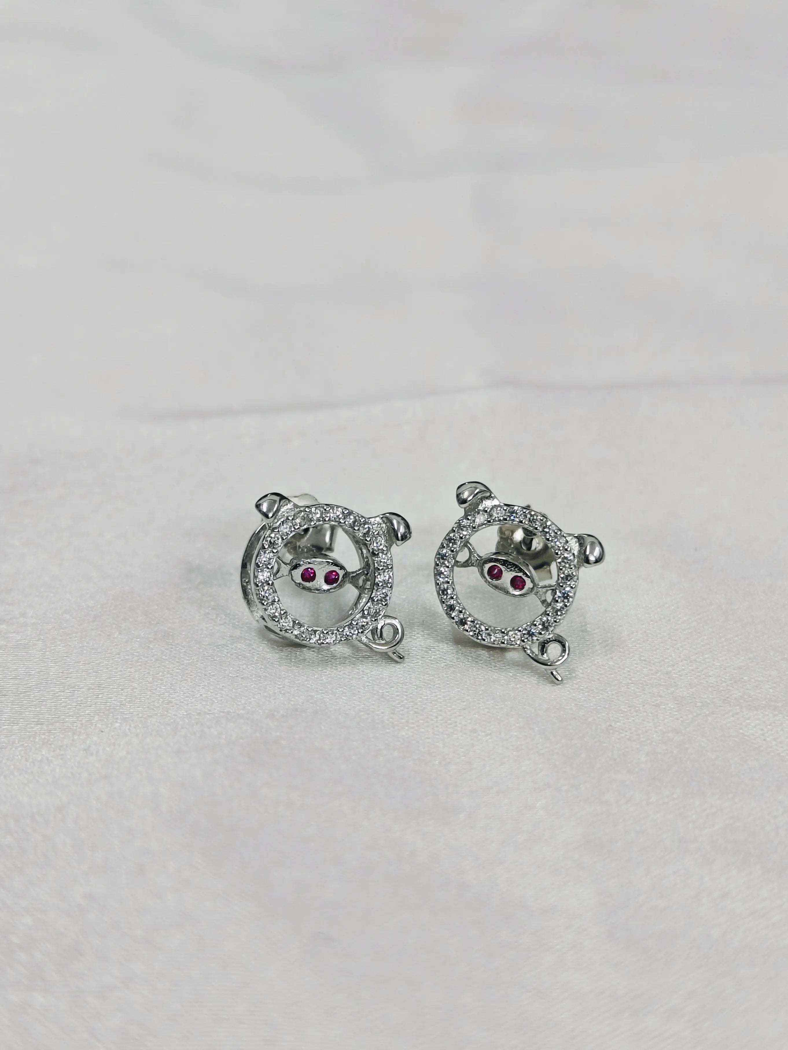 Pair of silver earrings with gemstones on a light gray background