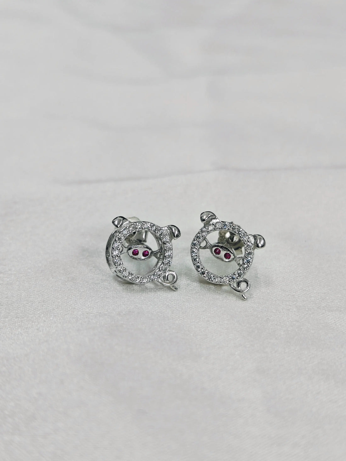 Pair of silver earrings with gemstones on a light gray background