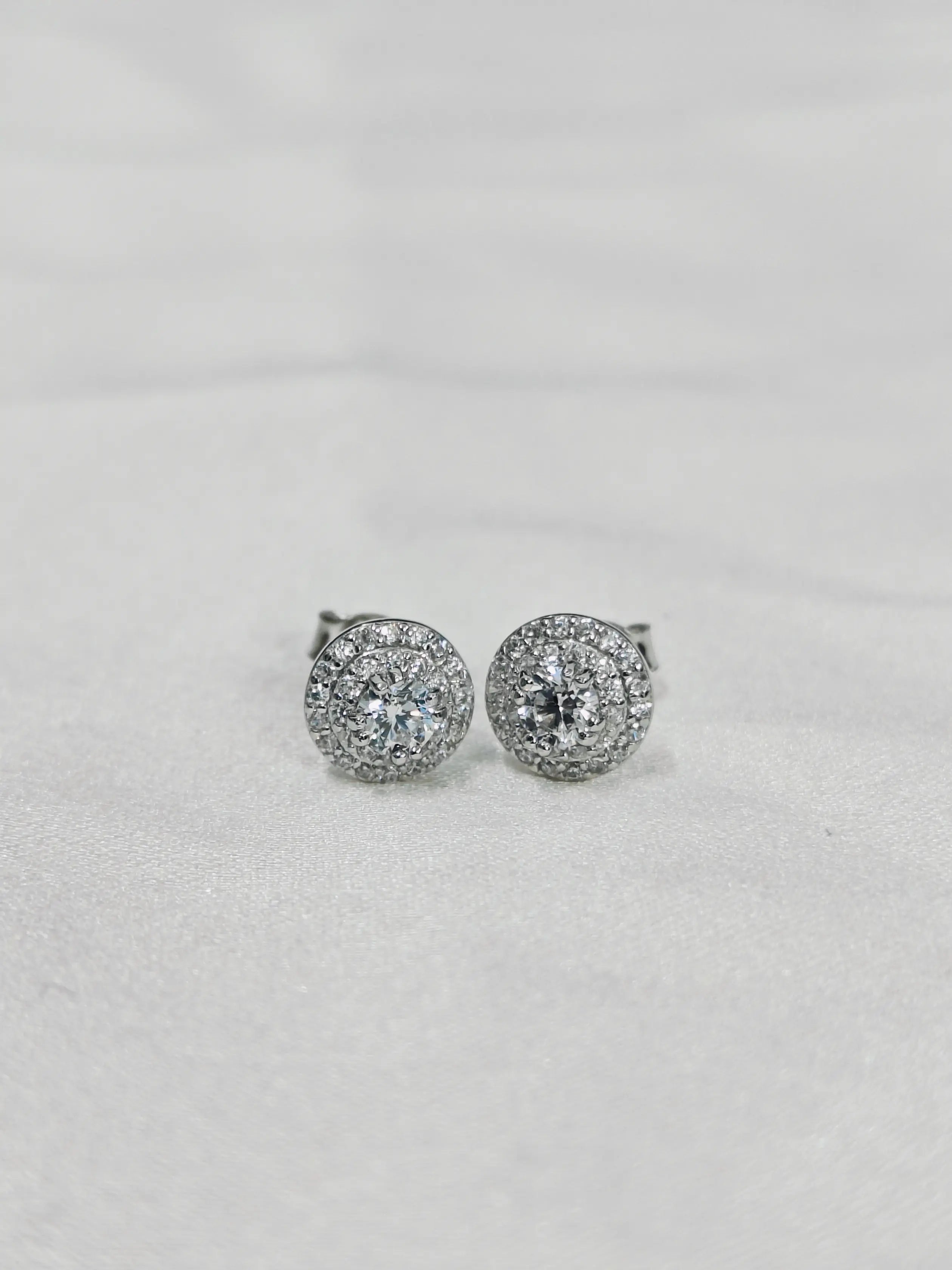 Pair of silver earrings with clear stones on a light gray background