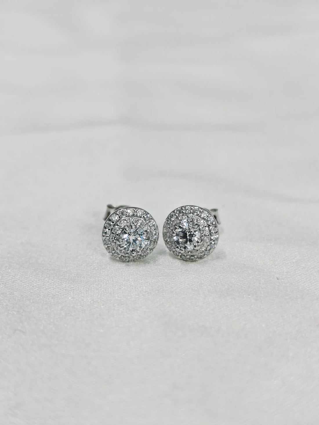 Pair of silver earrings with clear stones on a light gray background