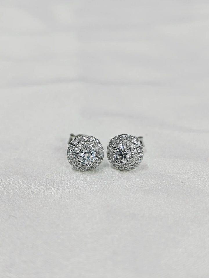 Pair of silver earrings with clear stones on a light gray background