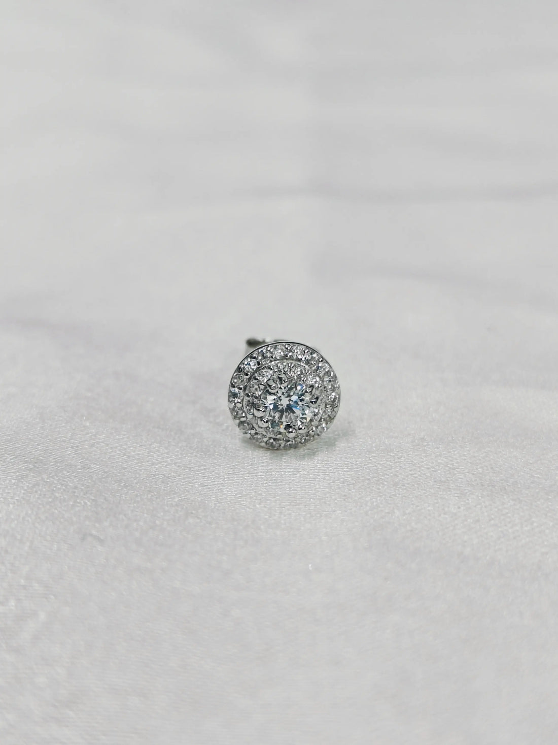 Silver earring with clear gemstones on a light gray background