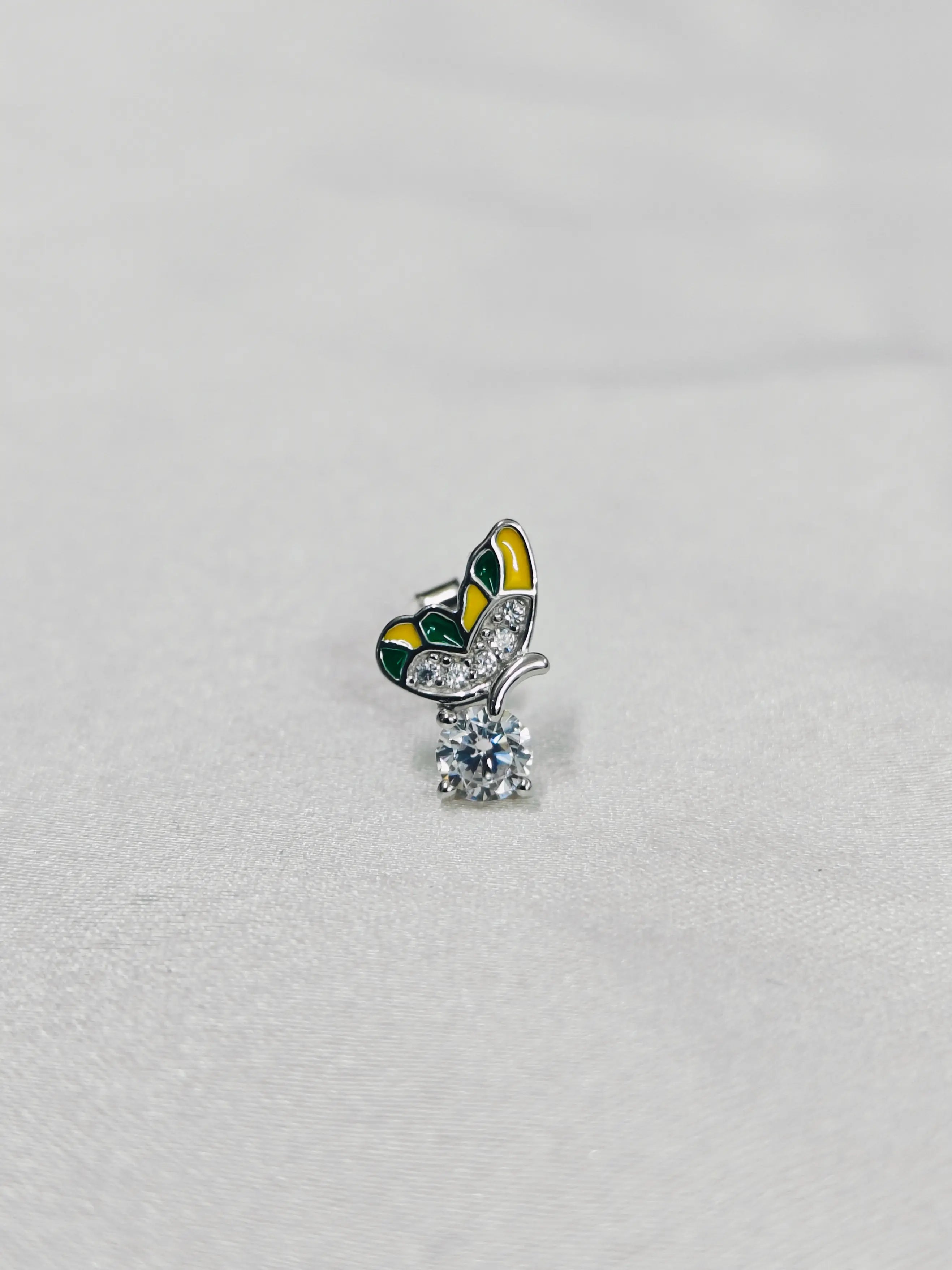 Butterfly-shaped brooch with a central gemstone on a light gray background