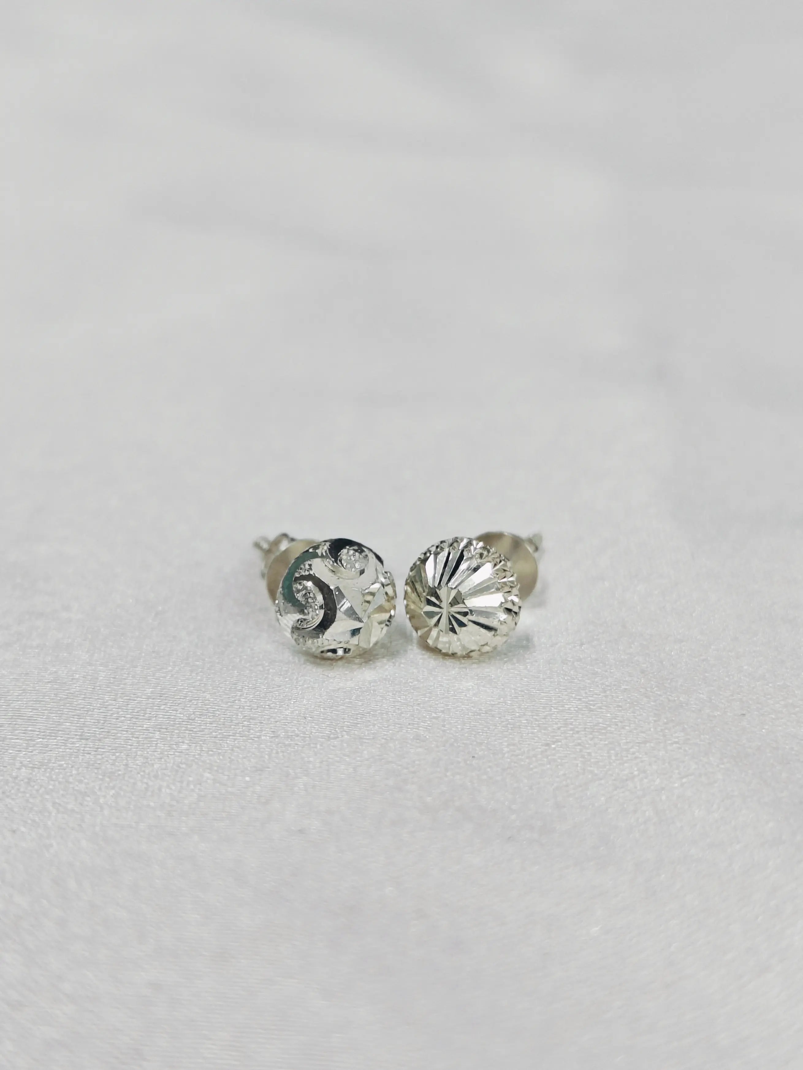 Silver stud earrings with clear gemstones on a light gray background