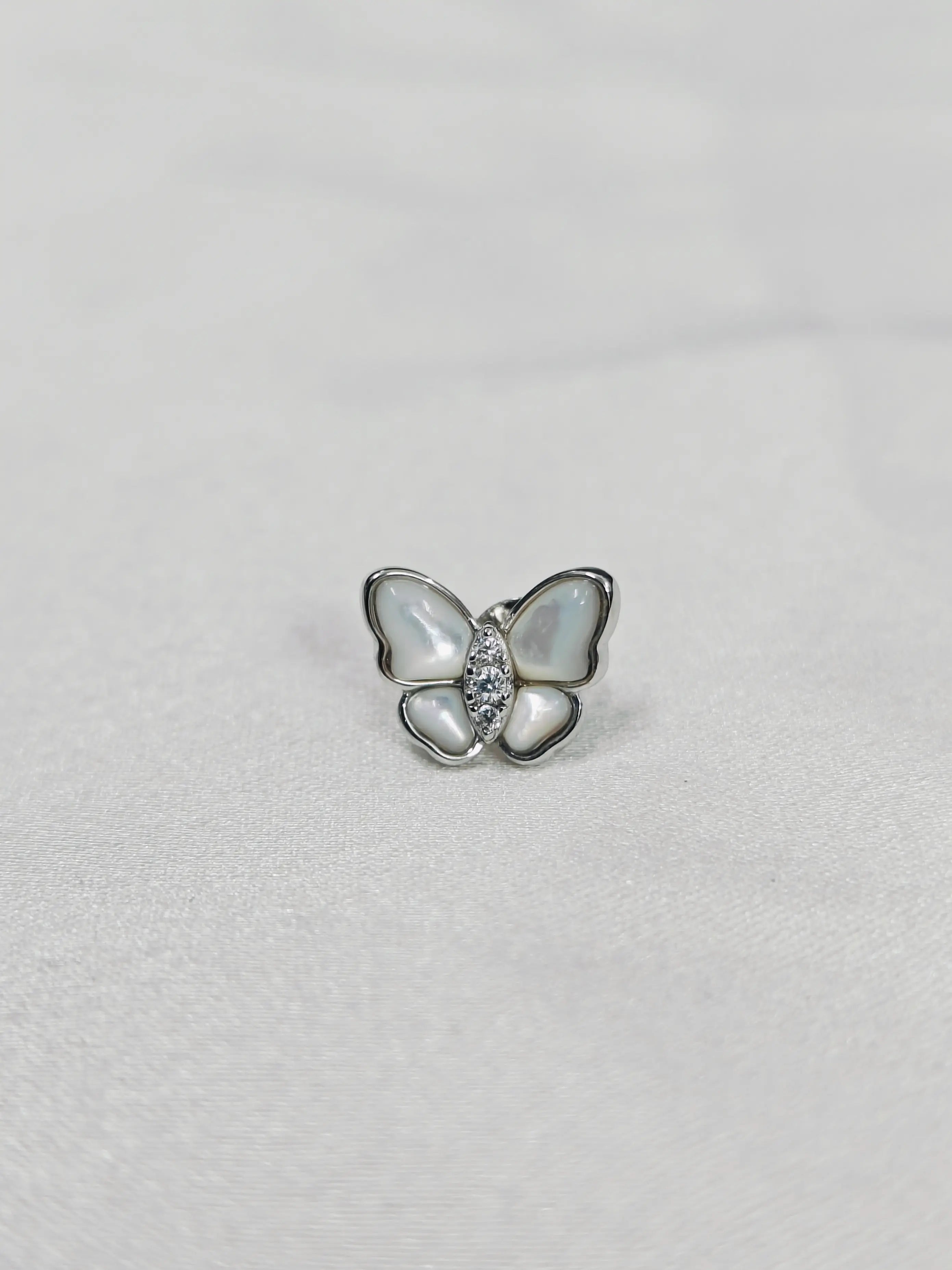 Butterfly-shaped earring with a gemstone on a light gray background