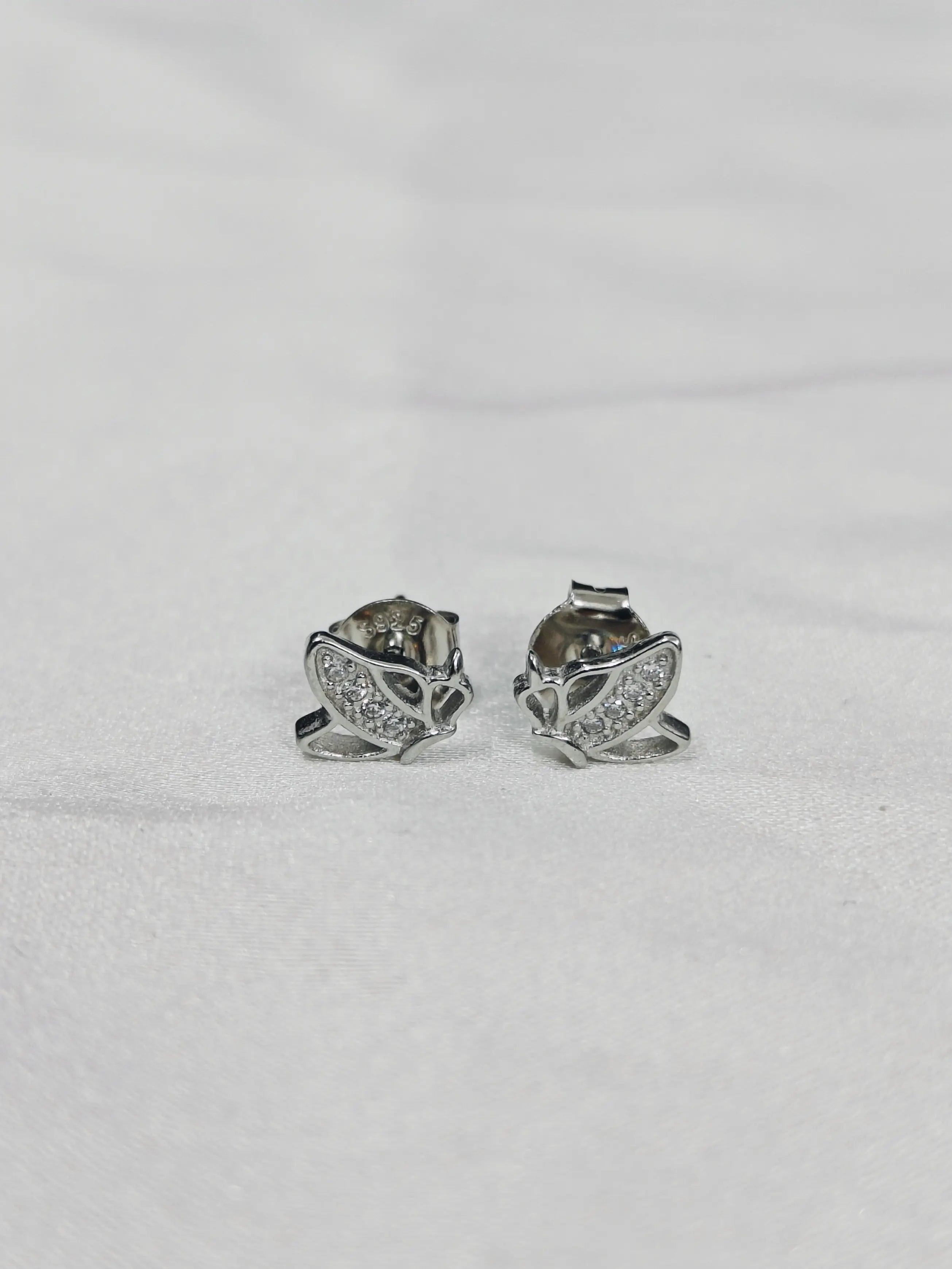 Pair of silver butterfly-shaped earrings on a light gray background