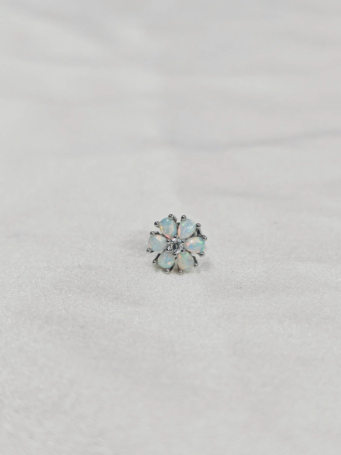 Single earring with opal stones on a light gray background