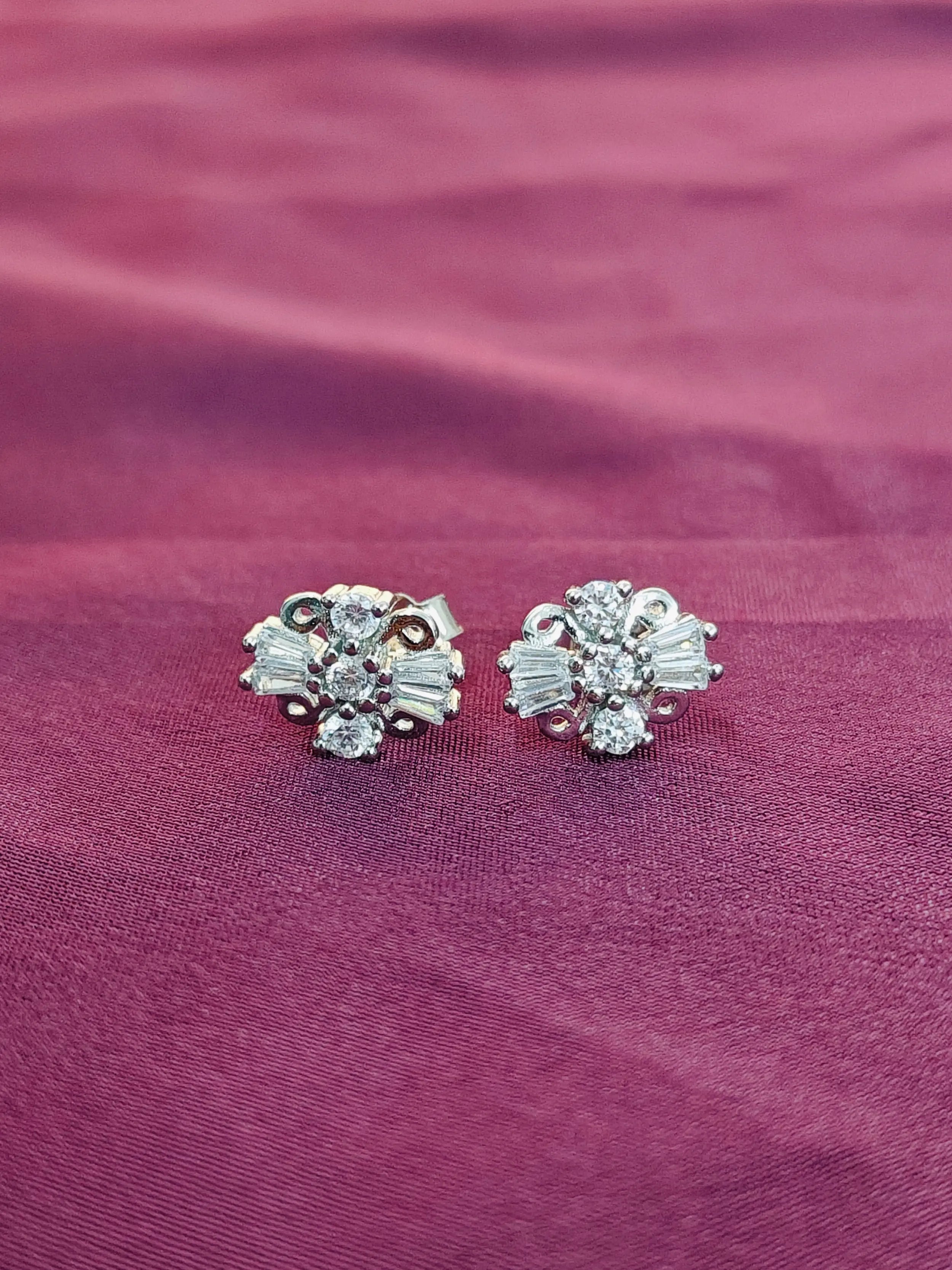 Pair of silver earrings with gemstones on a purple fabric background