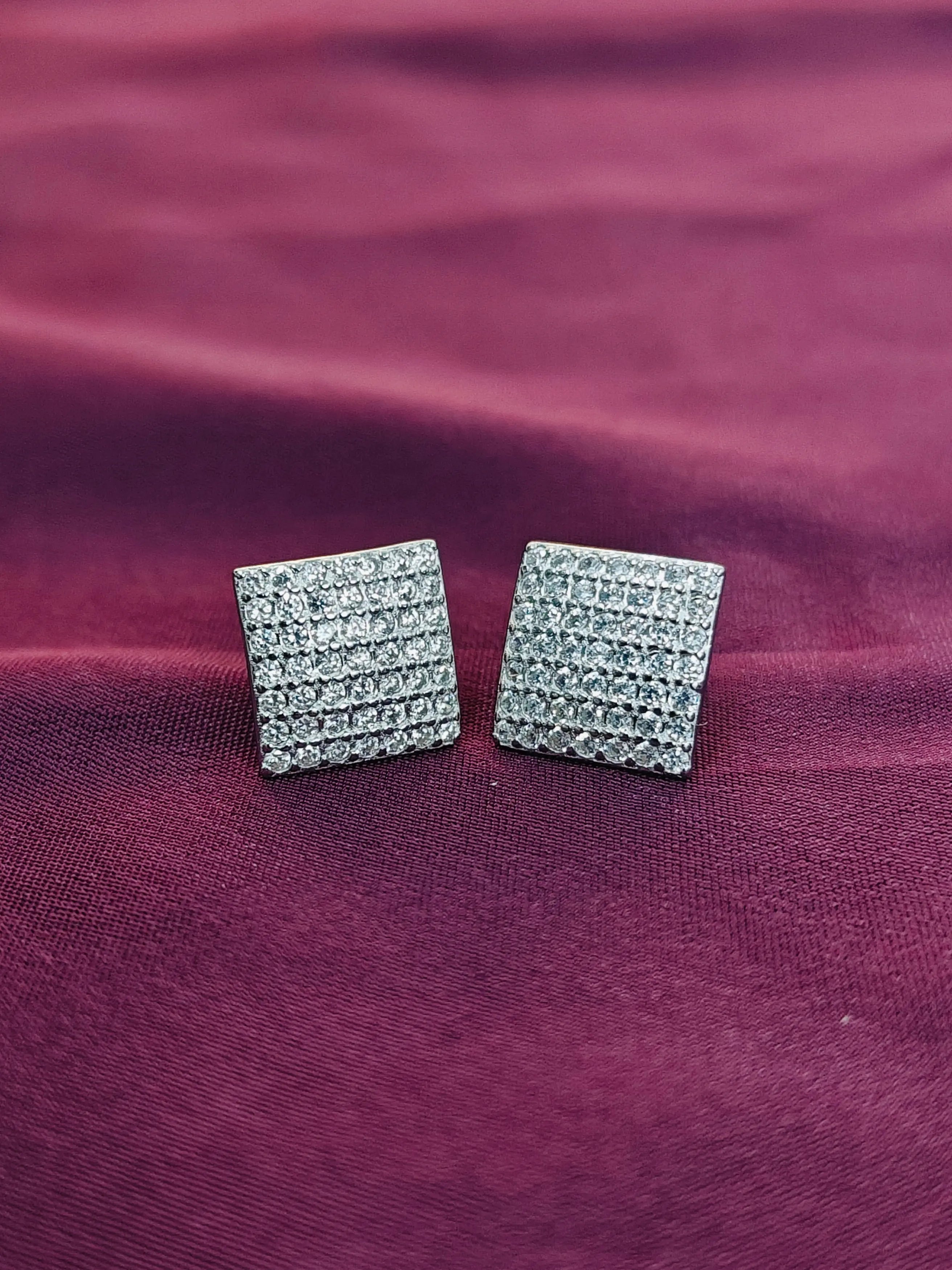 Square crystal stud earrings on a purple fabric background