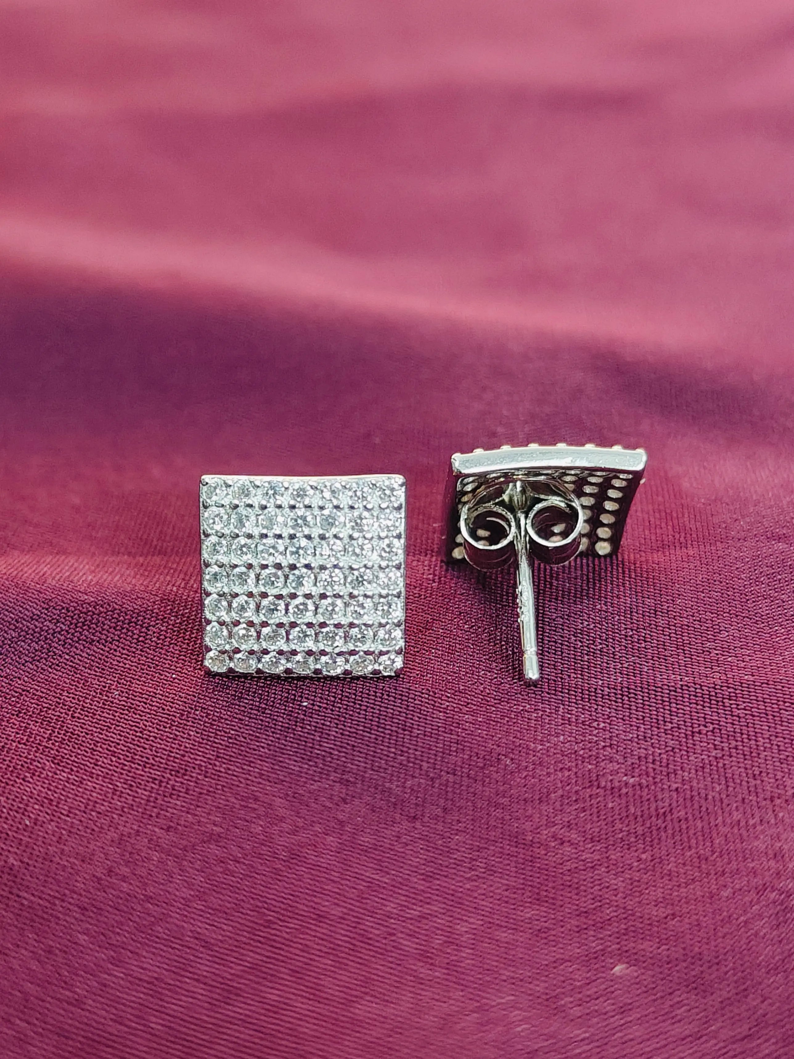 Silver square earring on a pink fabric background