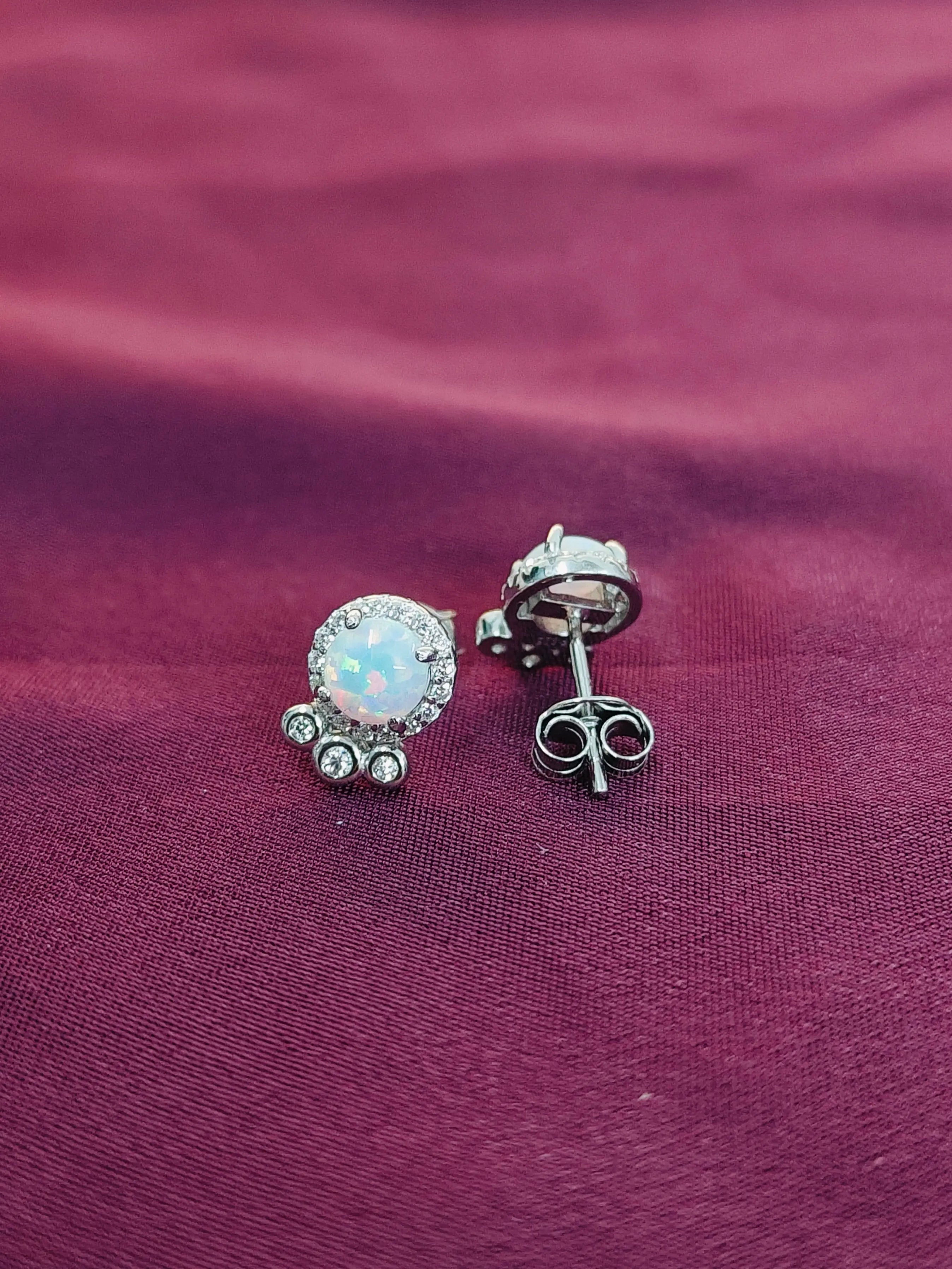 Silver earrings with a central gemstone on a purple fabric background