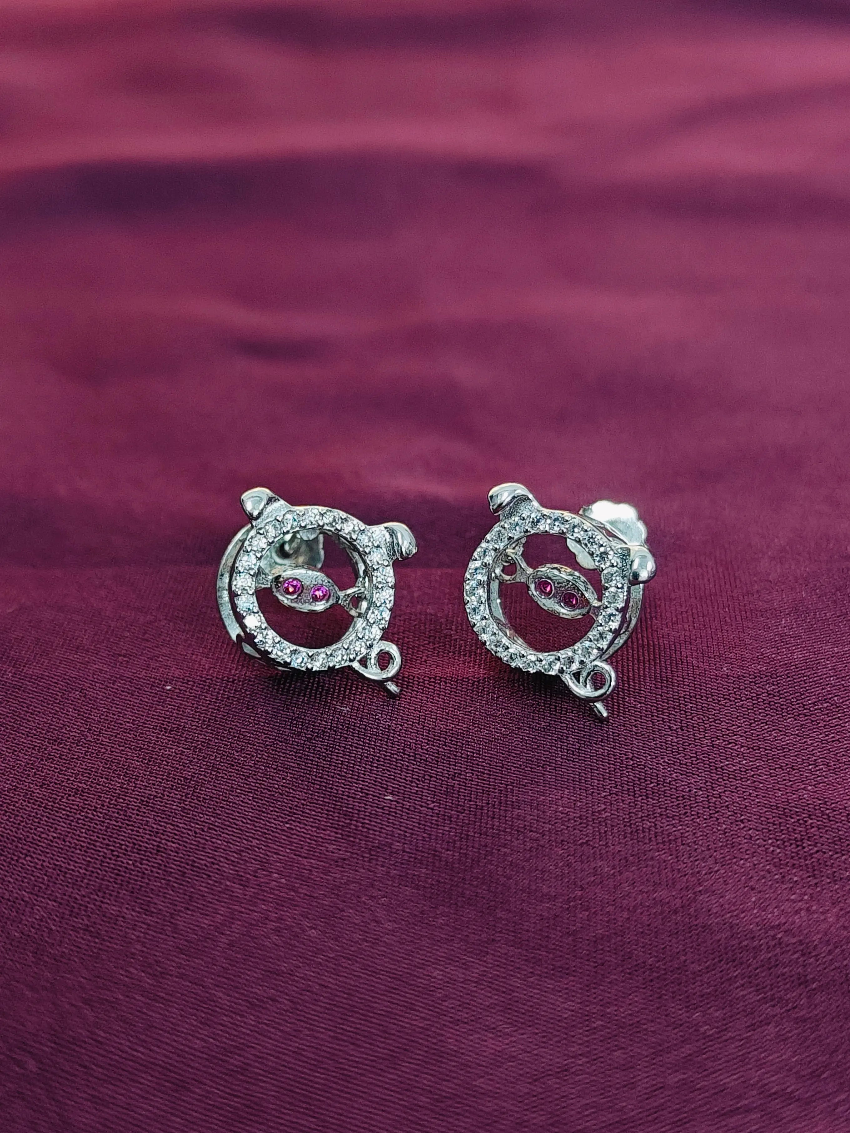 Silver earrings with gemstones on a purple fabric background