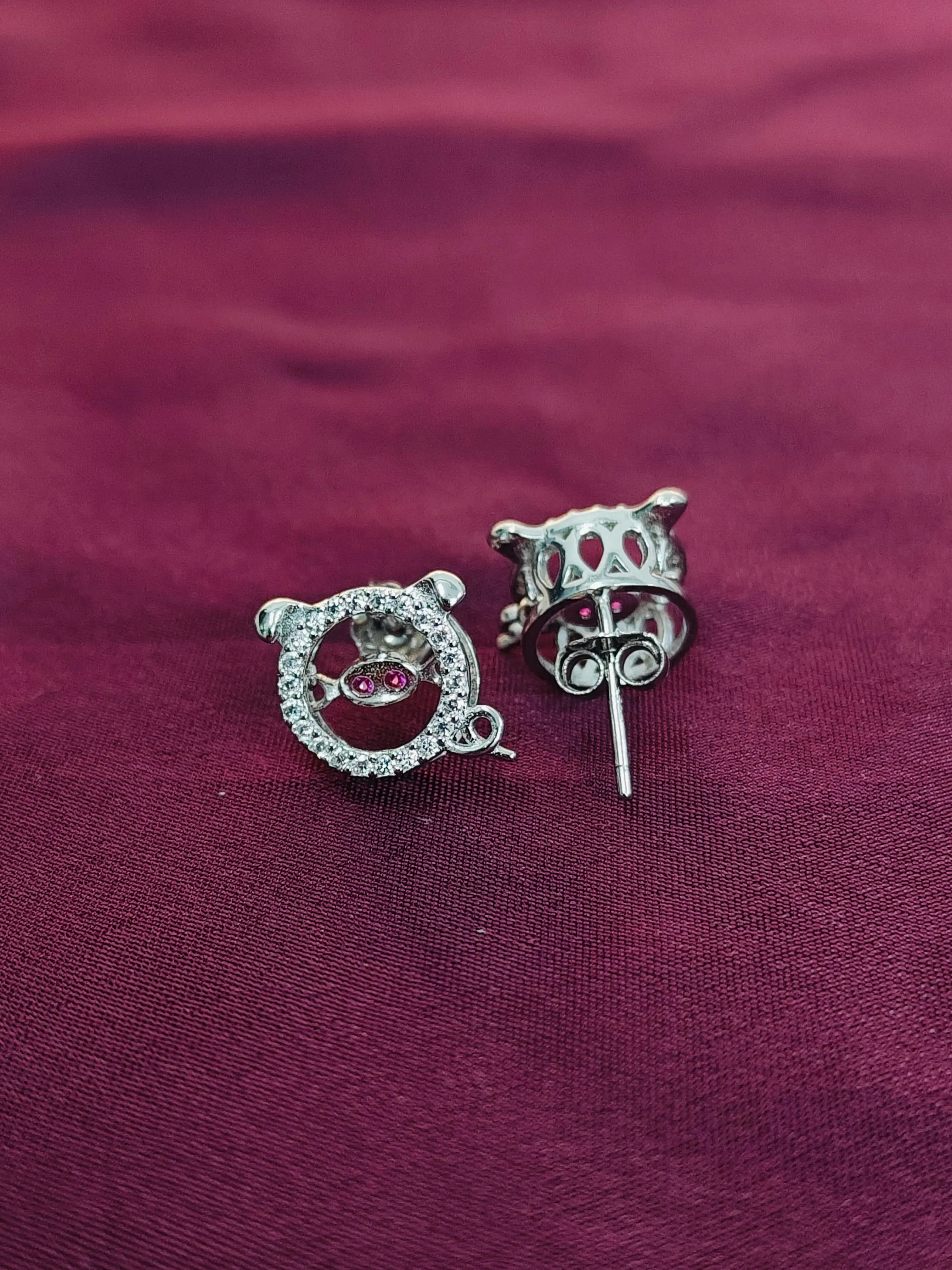 Pair of silver earrings with gemstones on a maroon fabric background